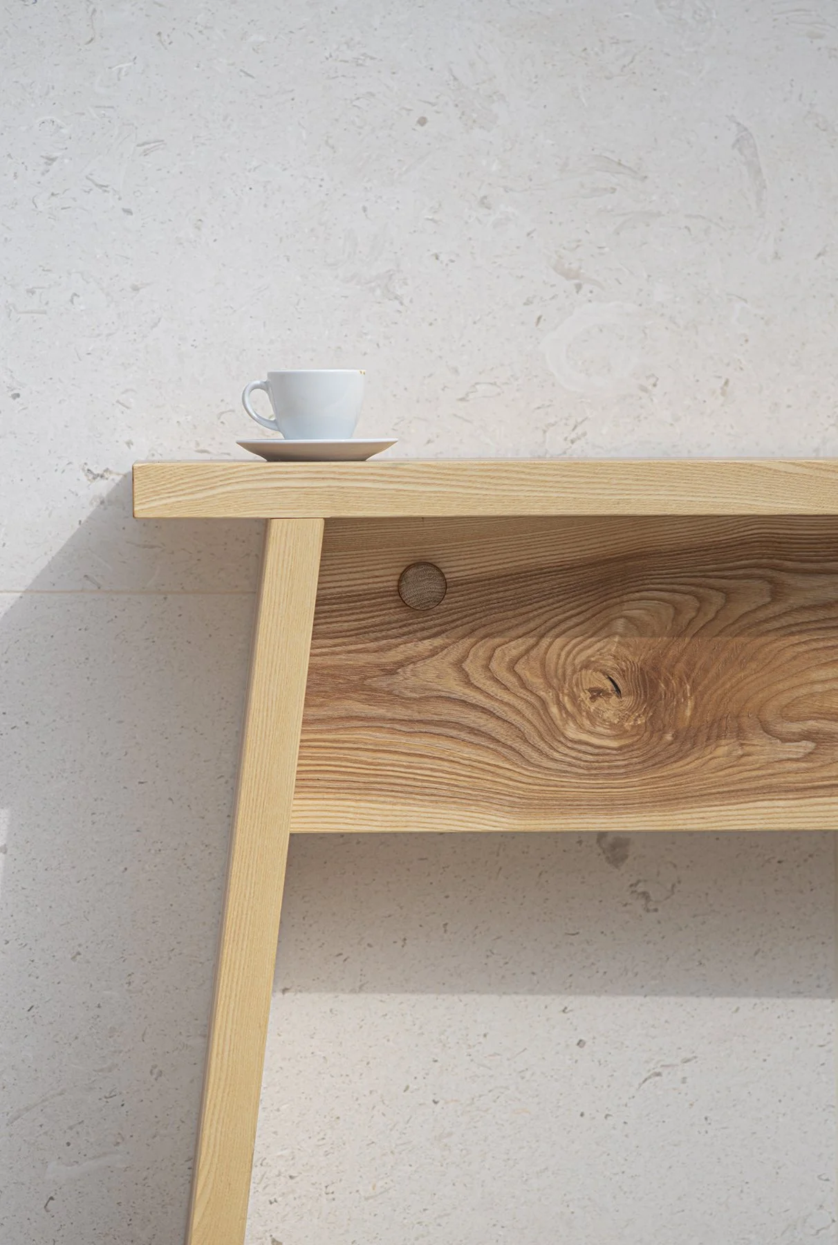 Detail dřevěného stolku ŠTOK od Egoé u minimalistické betonové stěny, produktová fotografie nábytku