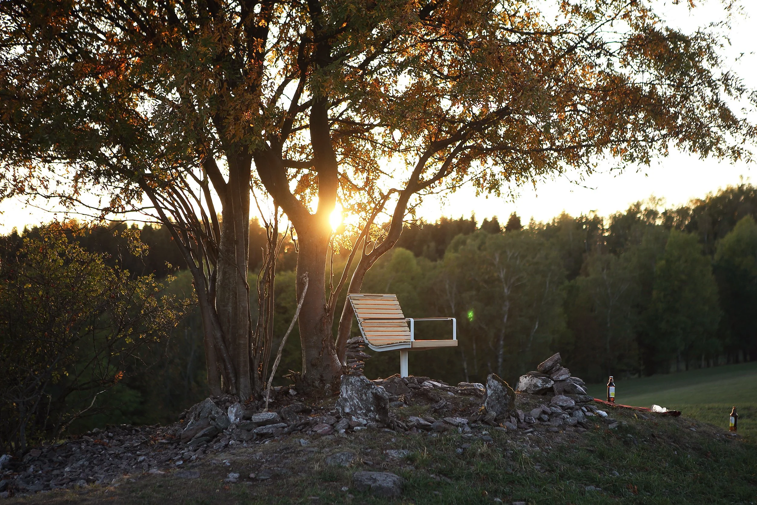 Lifestyle vizuál značky Egoé: designová dřevěná lavička v přírodním prostředí při golden hour, reprezentující estetický a přírodní styl produktové fotografie.