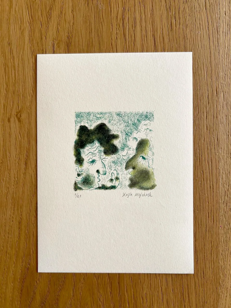 An artistic watercolor illustration of two women in profile facing each other. The drawing features abstract, swirling green, black, and yellow colors. The artwork is signed by Keja Mojzesh and numbered 1/21.