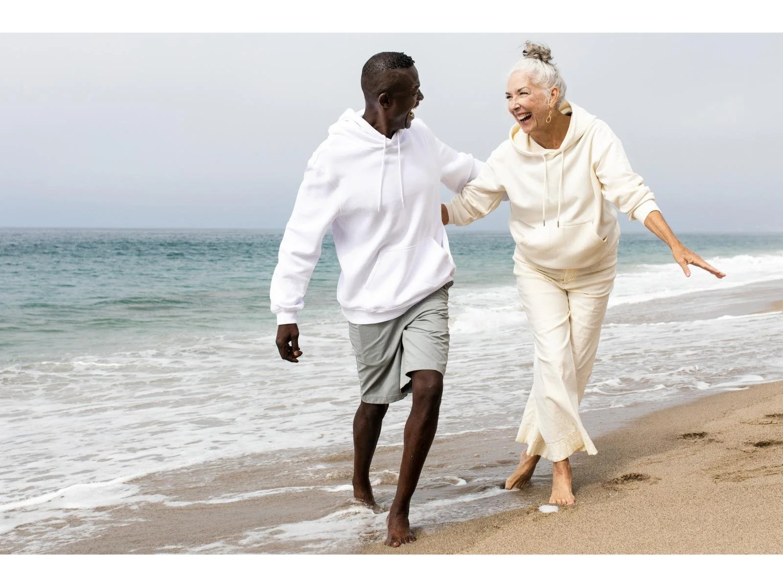 Happy senior couple walking barefoot on beach, enjoying pain‑free stride; mobility, balance and foot health with custom orthotics and care by registered chiropodist Canadian Foot Clinic & Orthotic Centre, St. Catharines ON.