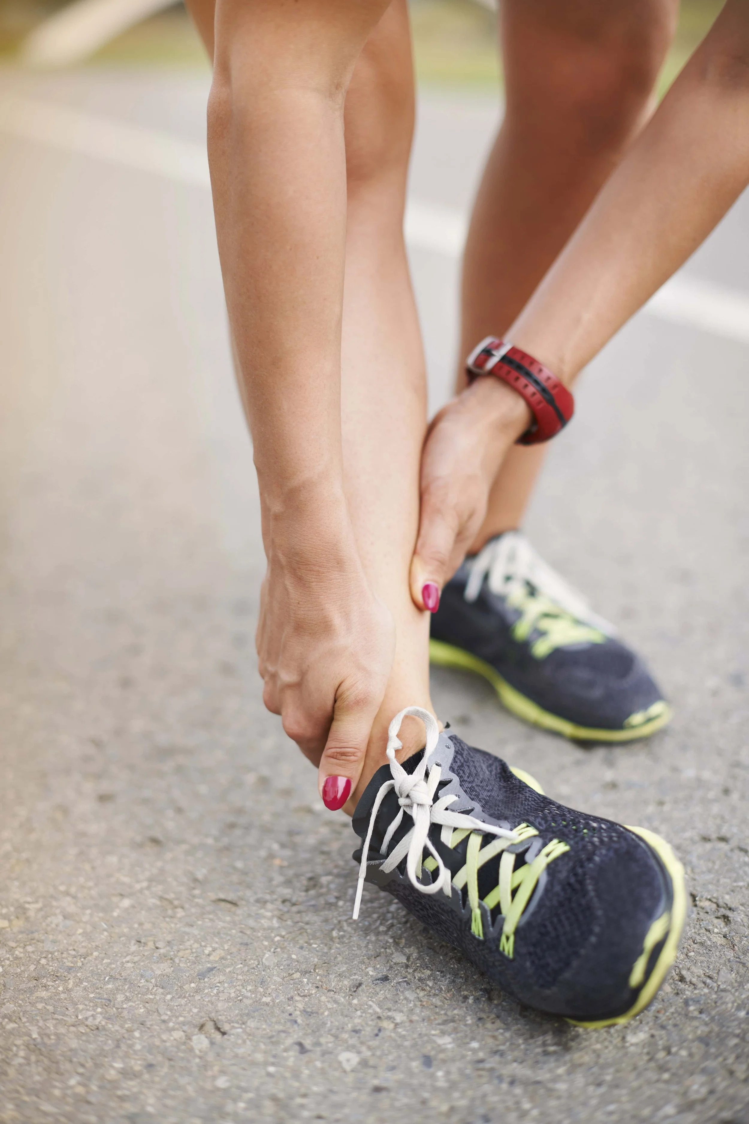 Woman runner clutching lower leg with shin splint pain; inflamed shin, overuse pain, gait correction, custom orthotics — registered chiropodist Canadian Foot Clinic & Orthotic Centre, St. Catharines.