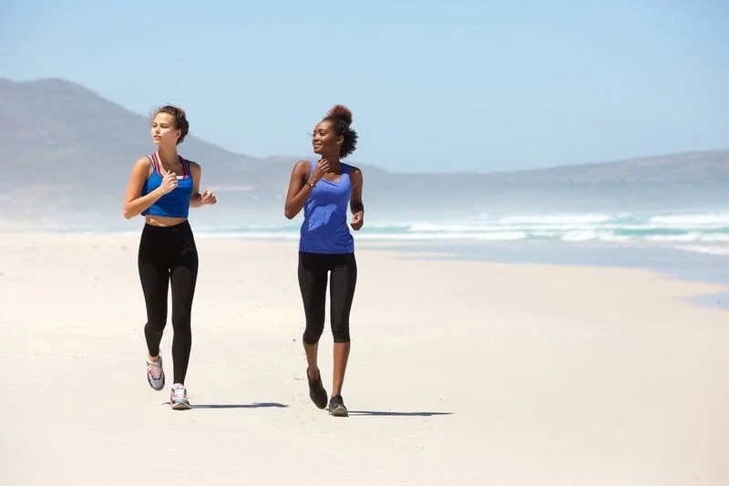 Two young women jogging on a sandy beach at sunrise; active runners, injury prevention, gait analysis, custom orthotics, foot care by registered chiropodist Canadian Foot Clinic & Orthotic Centre, St. Catharines.