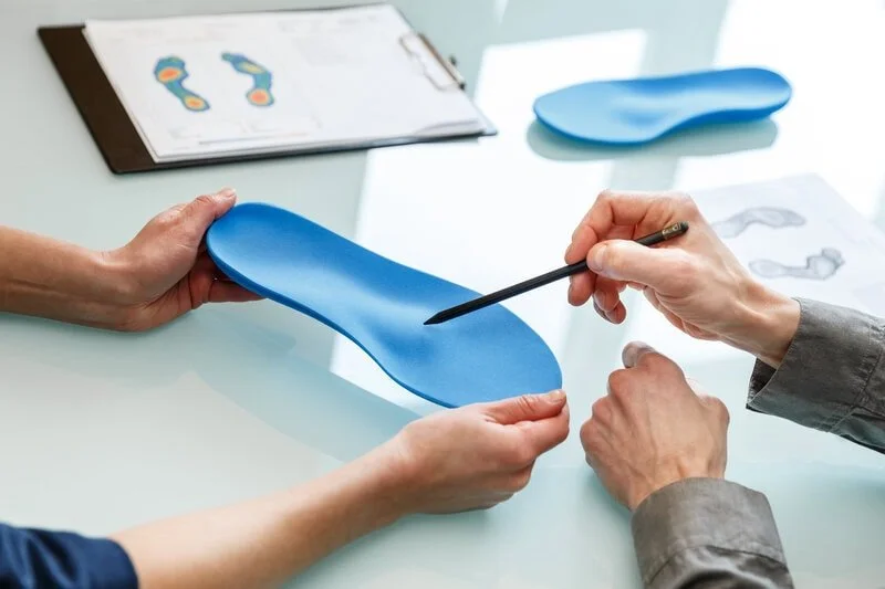 Podiatrist chiropodist consulting patient about custom orthotics — gait analysis, foot scan and orthotic fitting; expert chiropodist care, pain relief and posture support by Canadian Foot Clinic & Orthotic Centre, St. Catharines ON.