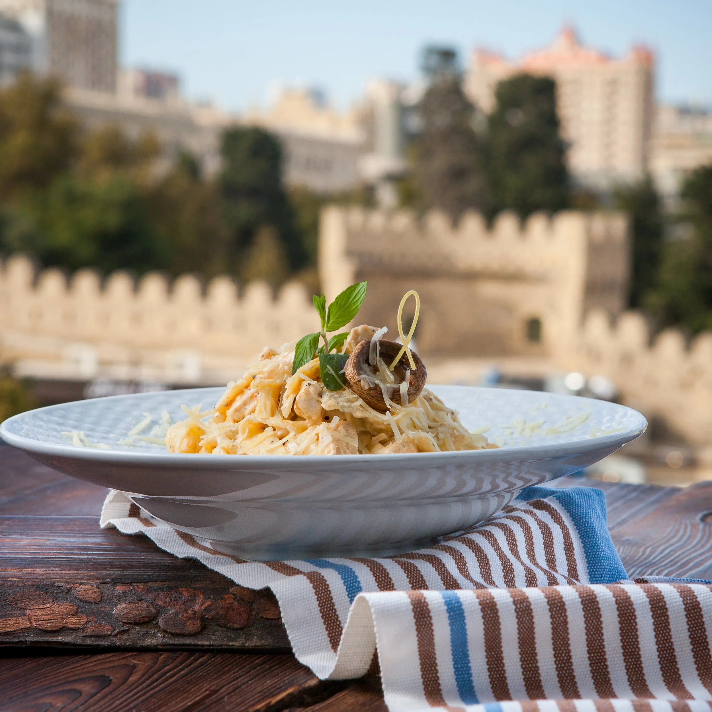 side-view-pasta-with-cheese-mushrooms-white-plate-dark-wooden-table-with-city-view.jpg