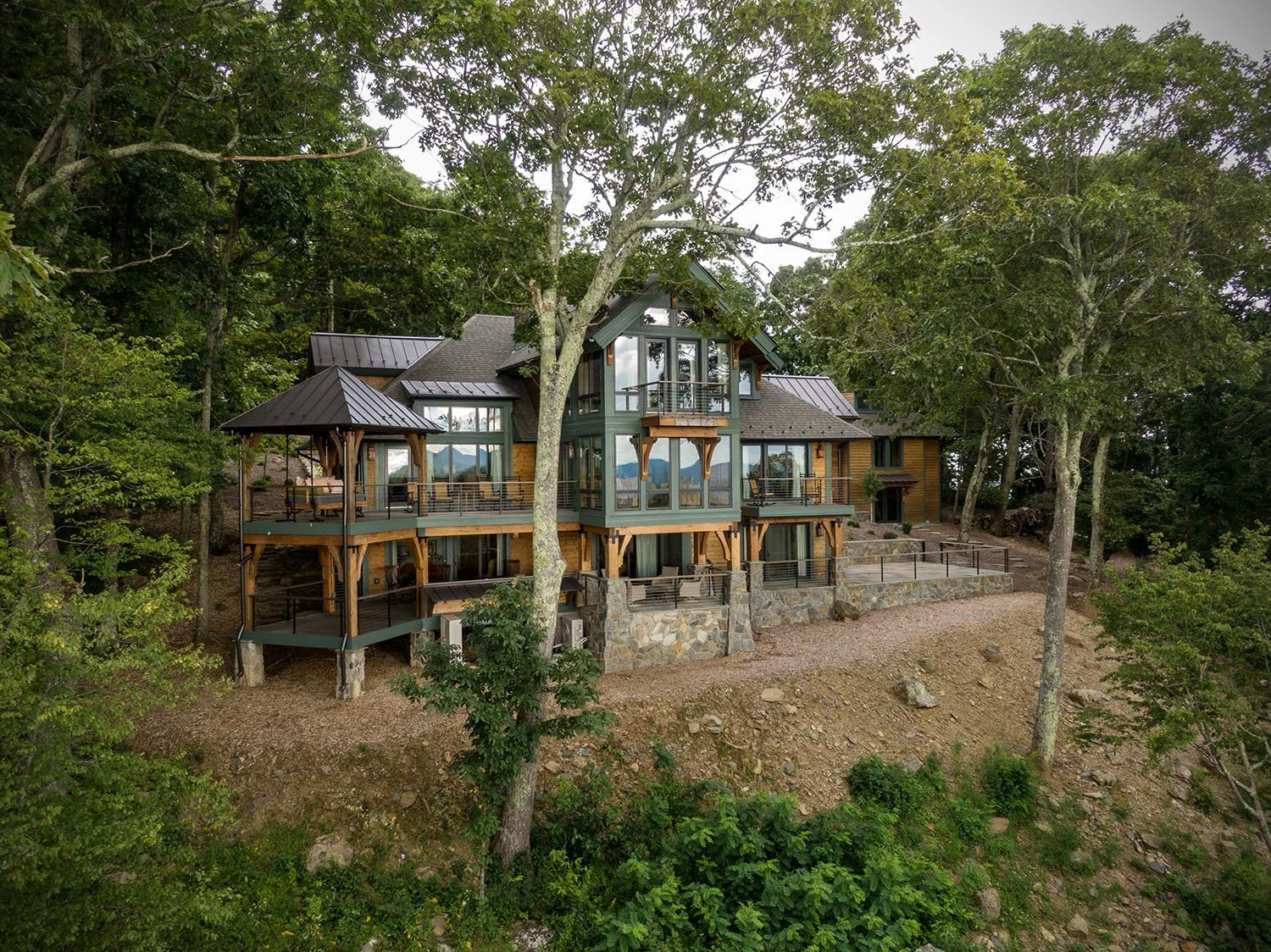 A large modern house with multiple decks surrounded by trees on a hillside.