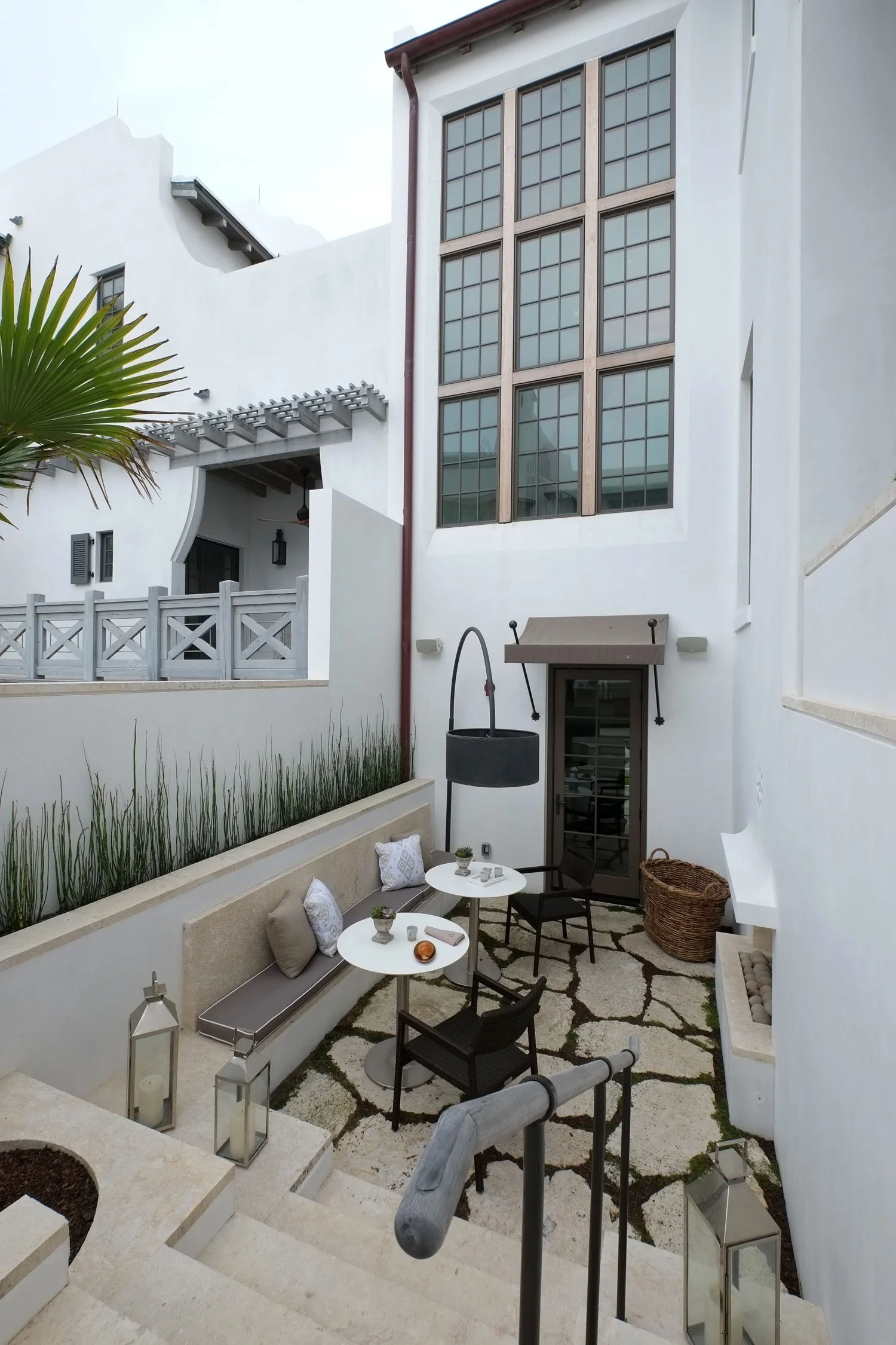 Patio area with white walls, seating, tables, and outdoor decor in a modern house.