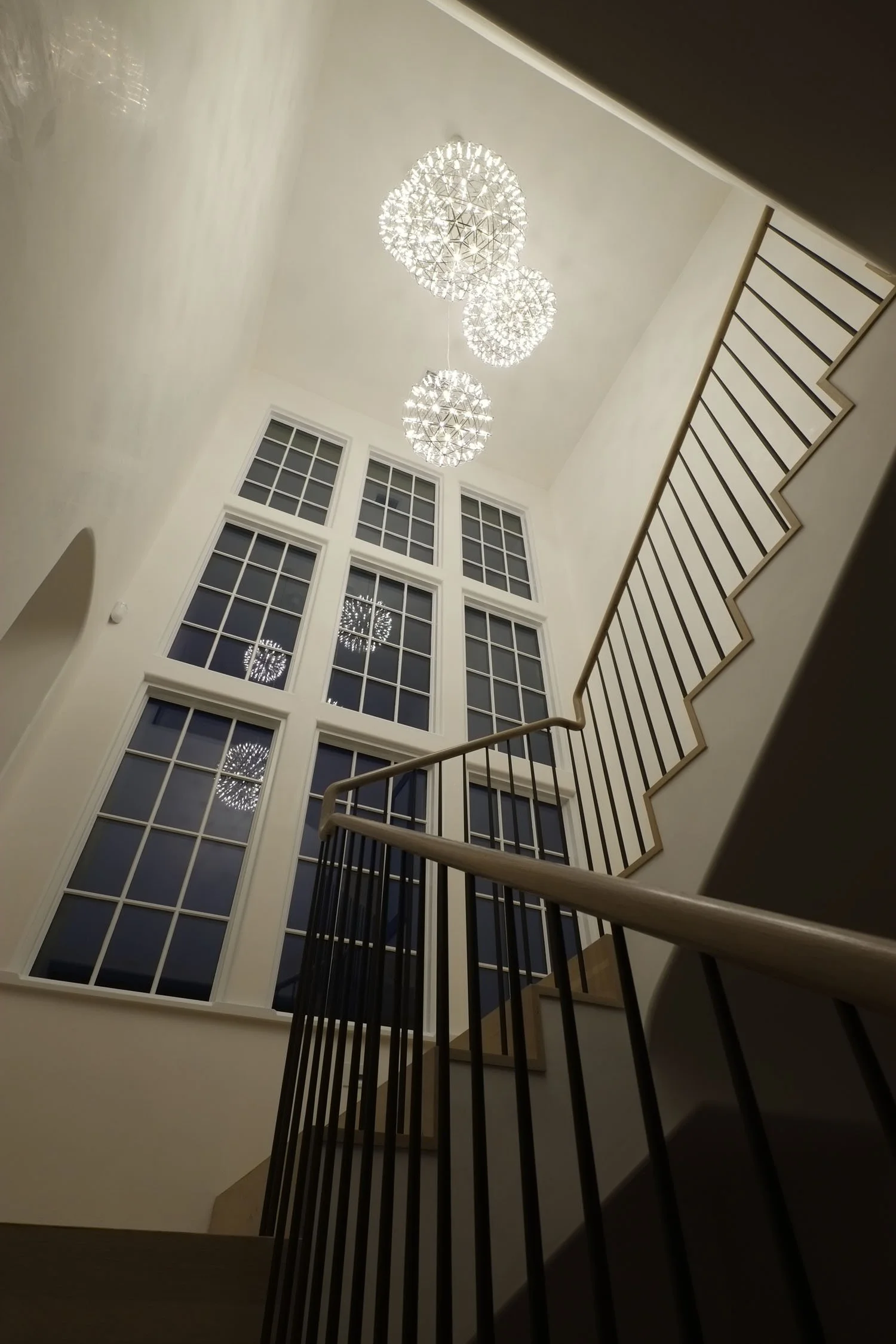 Interior view of a staircase with a large window and modern hanging chandeliers