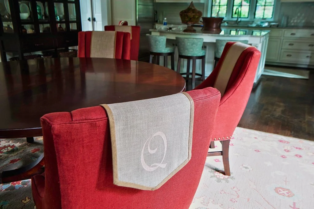 Red upholstered dining chairs with beige fabric accents around a dark wooden dining table in a kitchen and dining area.