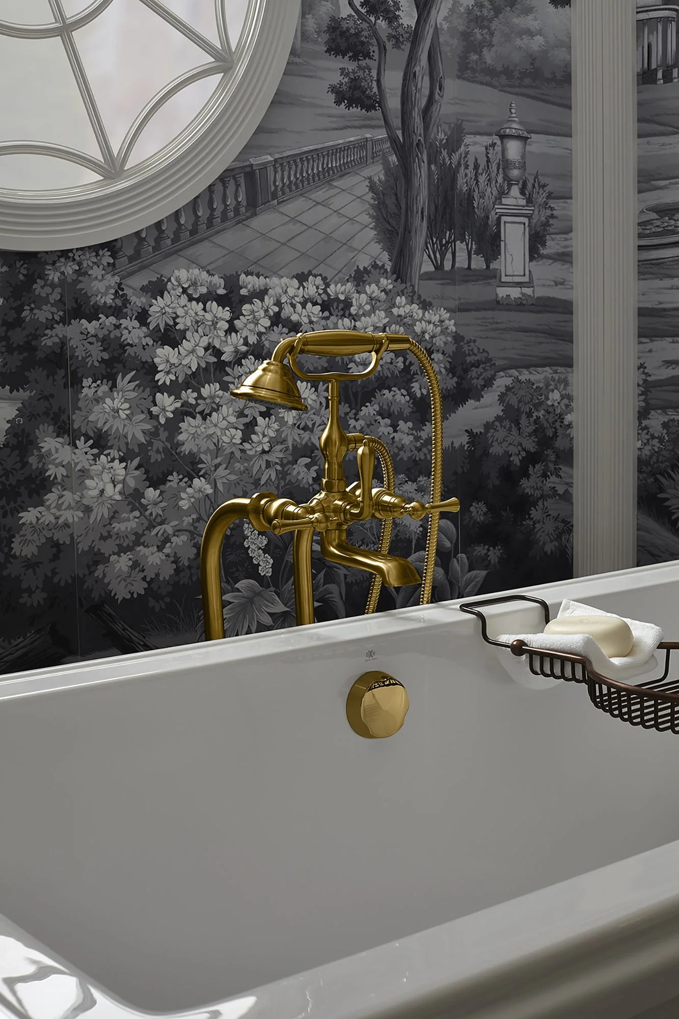 A white bathtub with a gold faucet, a bar of soap, and a soap dish. In the background, there's a black-and-white mural of a garden scene with trees, bushes, and a pathway.