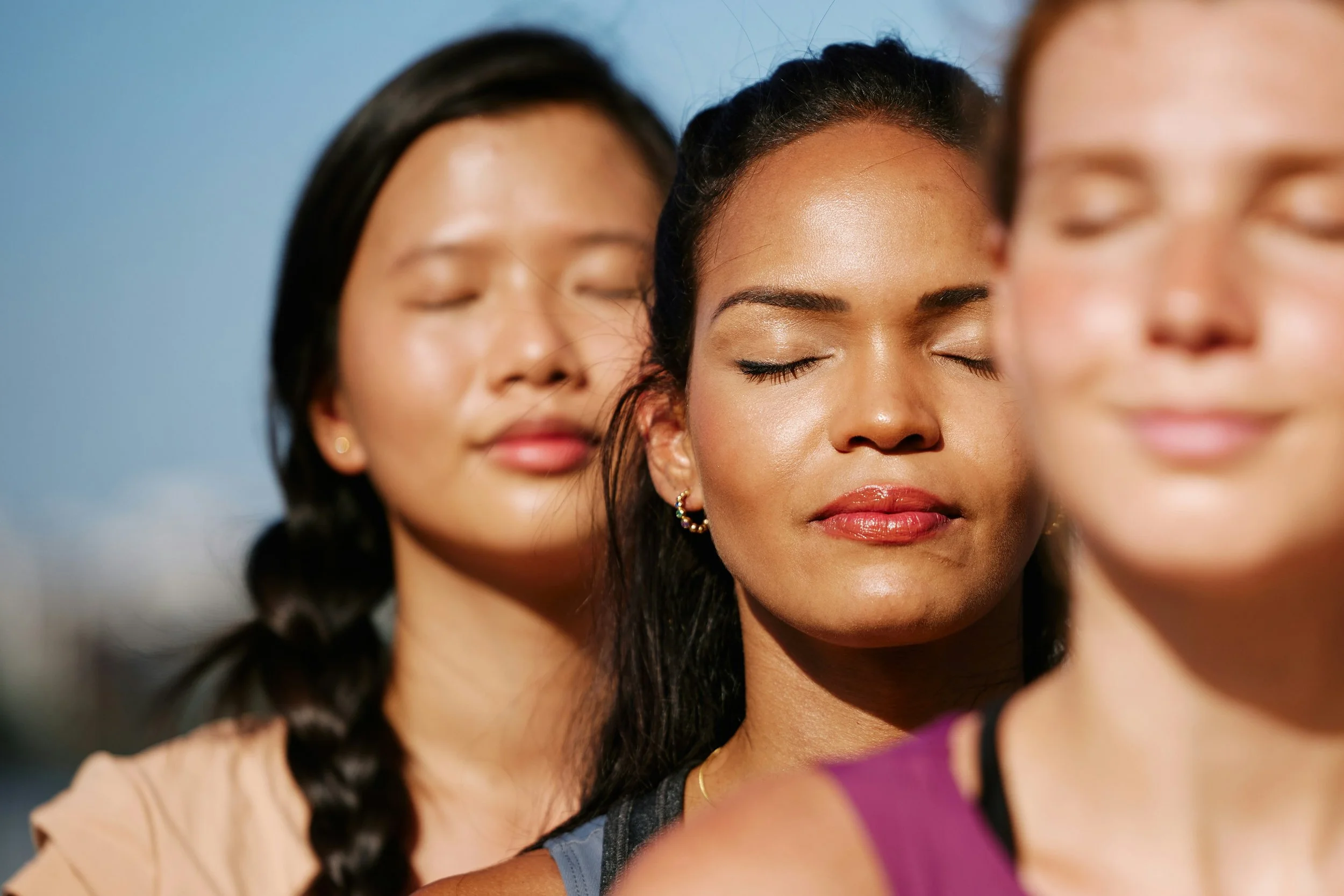 Three young women eyes closed in a meditative state 