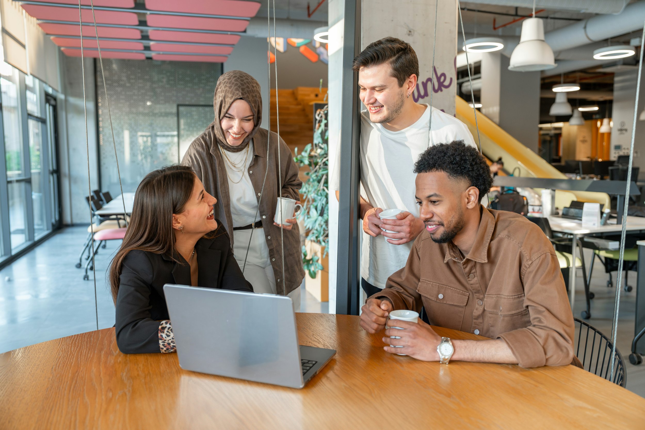 Group of colleagues around a laptop smiling and looking happy