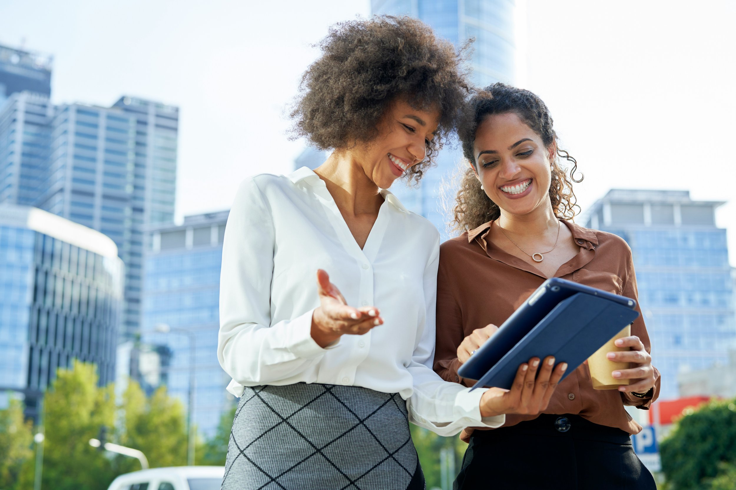 Two women looking at an i pad and smiling