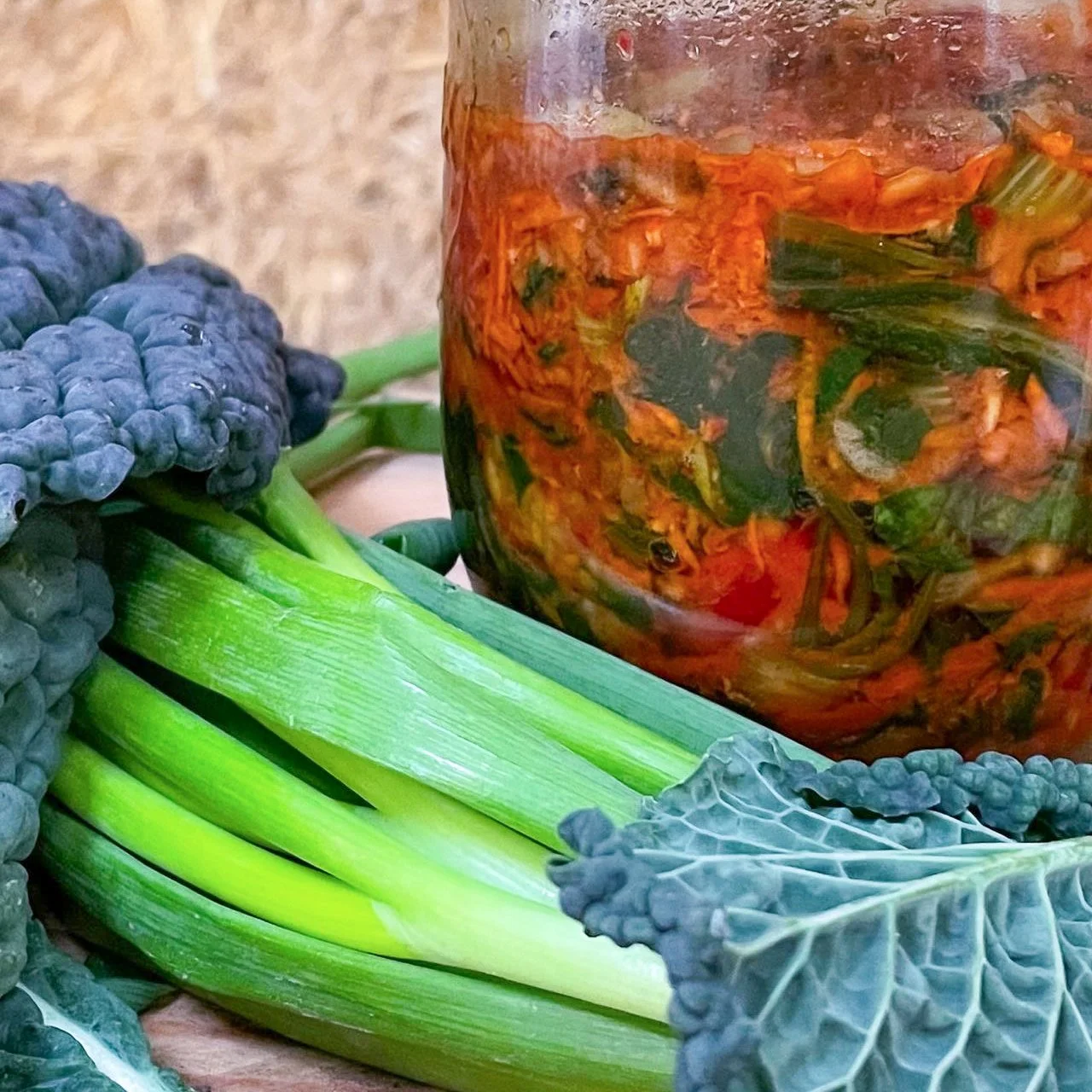 Groene uien en blauwe boerenkool naast een pot met ingelegde groenten.