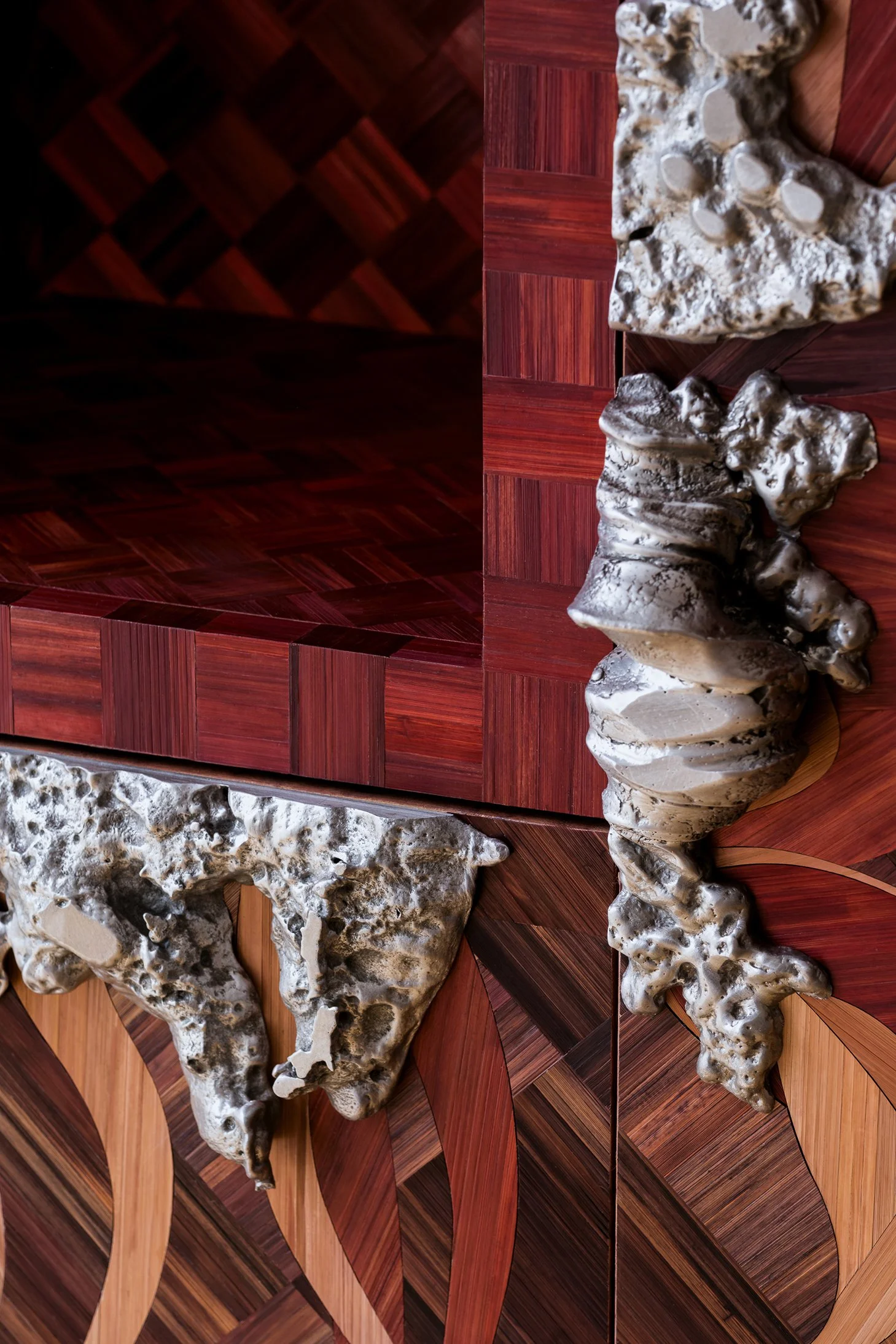 Close-up of a wooden table with mixed dark and light wood grain patterns and irregularly shaped textured metallic and stone elements on top.