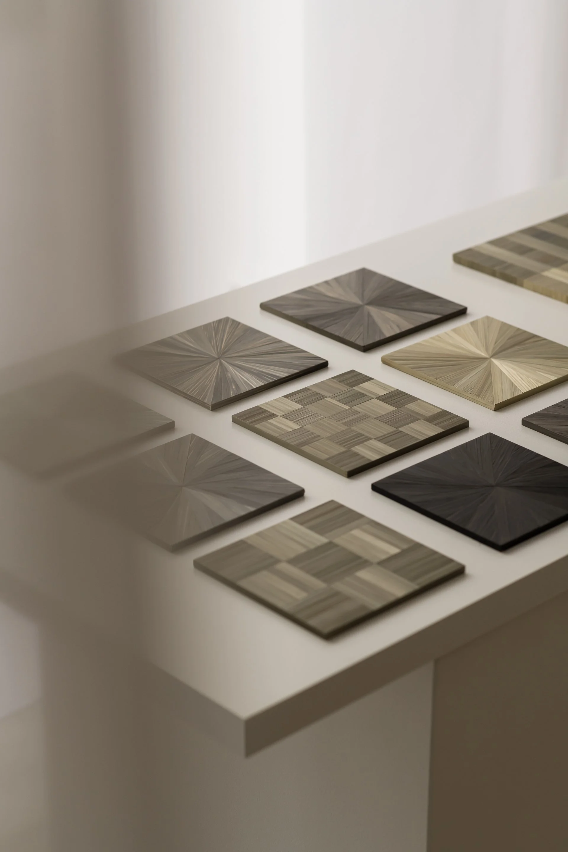 Collection of wood samples with geometric patterns, displayed on a white table.