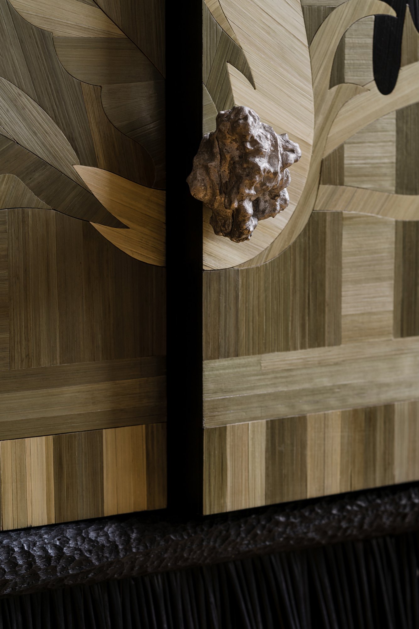 Close-up of a wooden decorative panel with a textured cast aluminium handle.