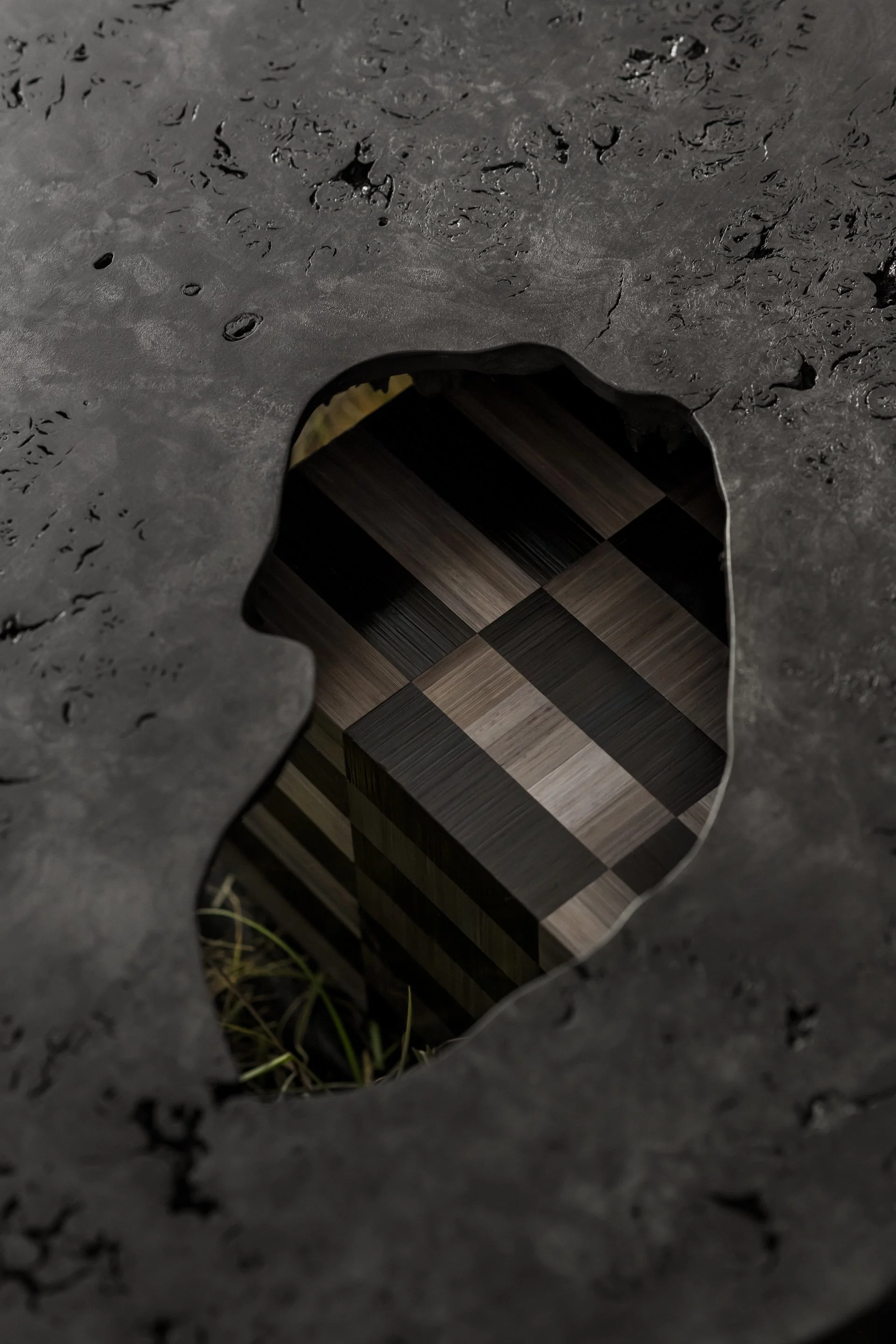 A close-up of a hole in a wet, dark surface, revealing a room with checkered wooden floors inside.