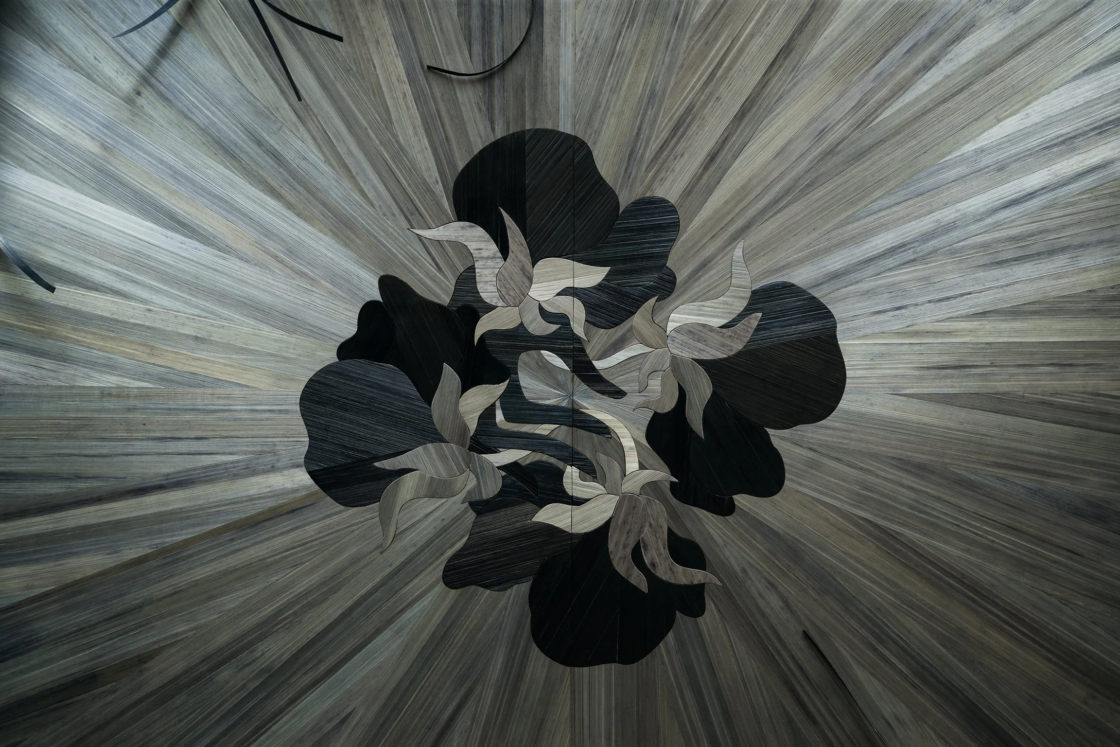 Ceiling mural with a large abstract floral pattern in black, gray, and beige, surrounded by radiant wooden planks.