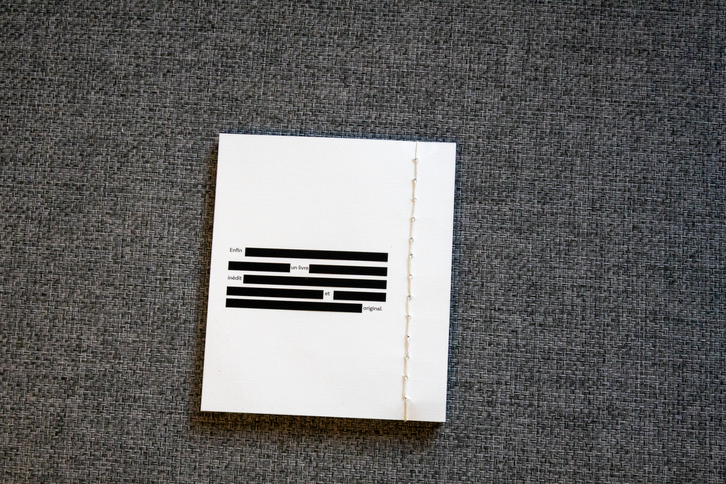 Page de livre avec texte en français masqué par des blocs noirs sur une surface gris foncé.