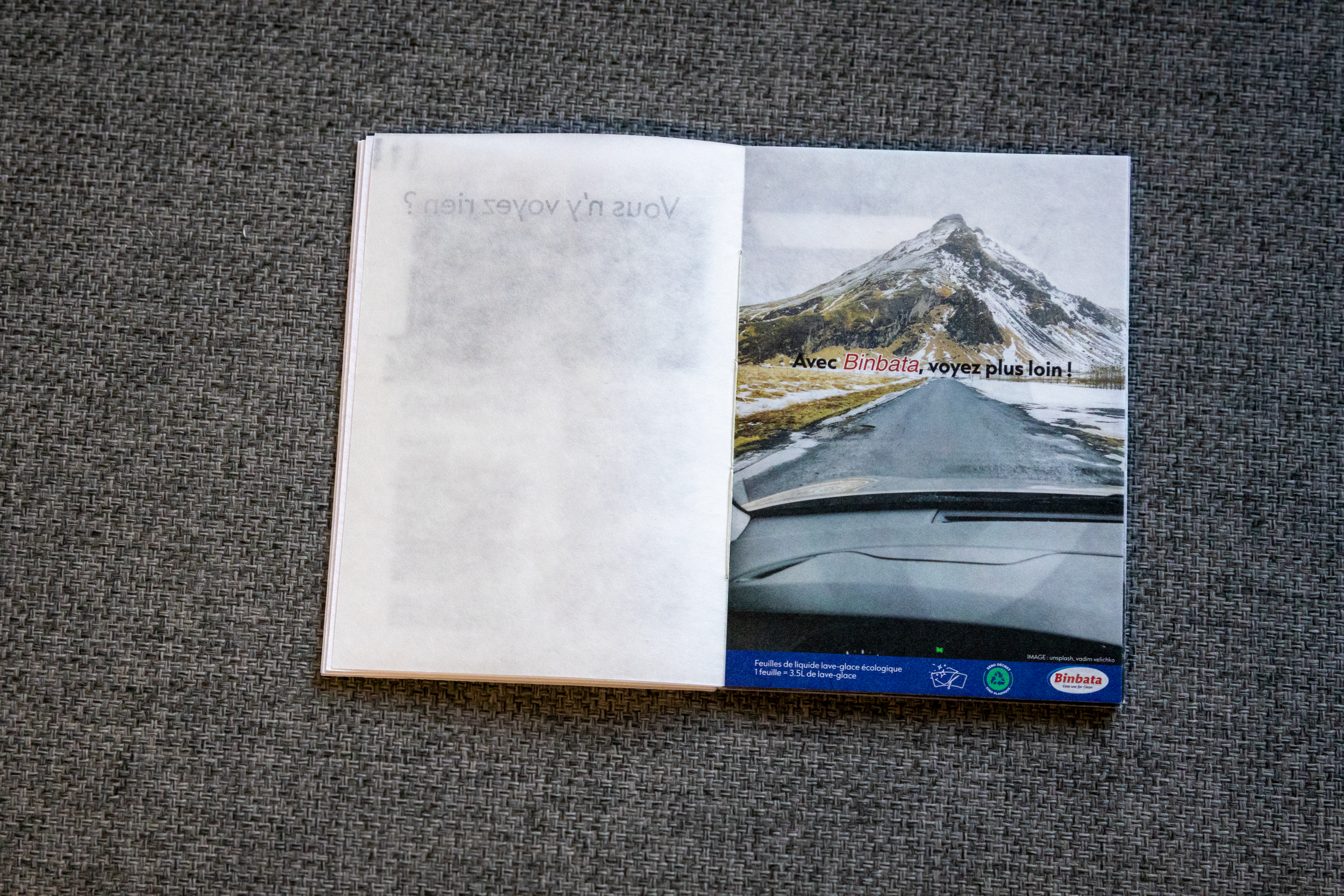 Page d'un magazine montrant une route menant à une montagne enneigée avec un ciel nuageux, texte en français "Avec Binbata, voyez plus loin !"