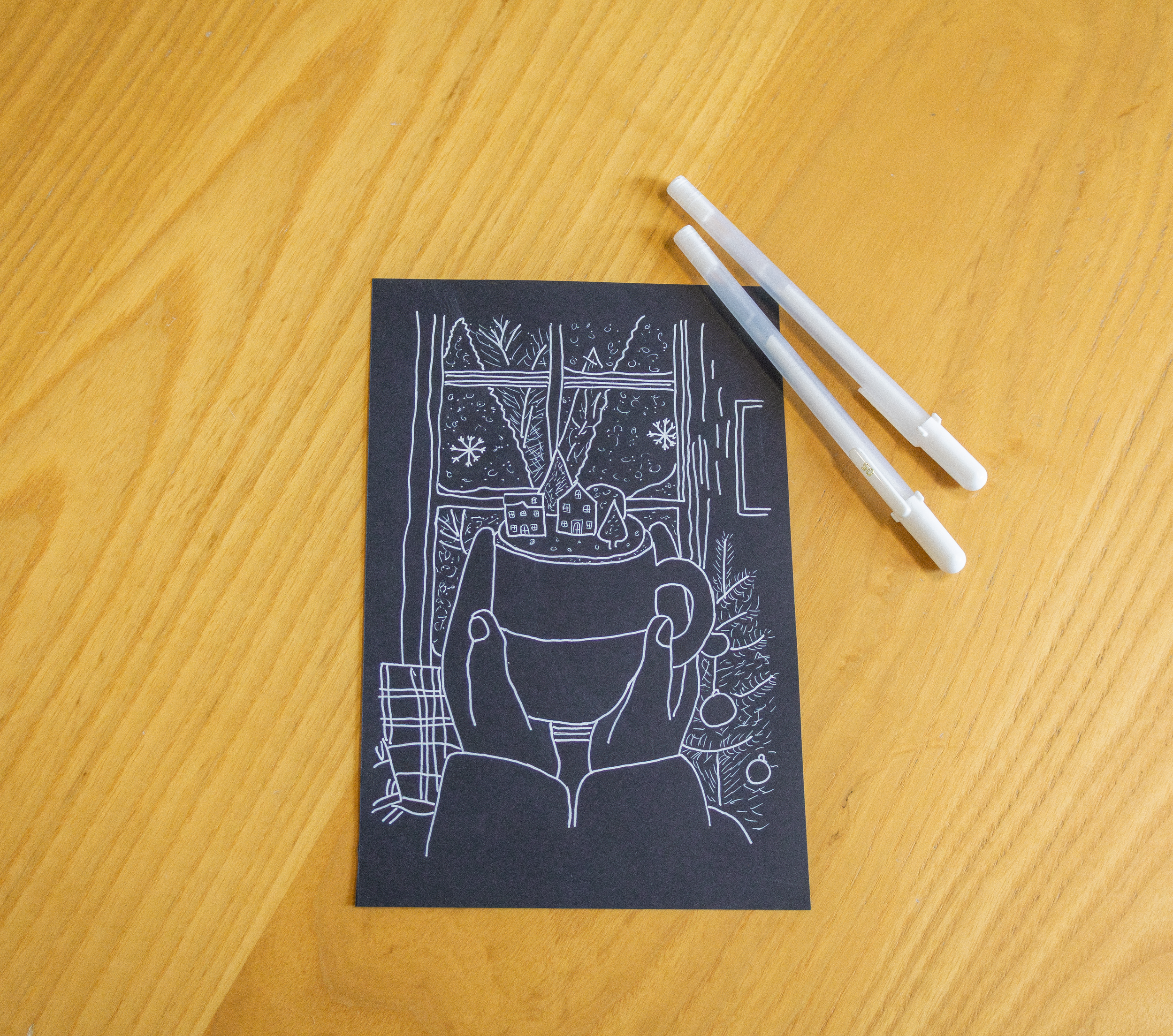 Dessin fait avec une craie blanche sur du papier noir représentant une vue intérieure d'une pièce avec une fenêtre, un mug, une plante et une décoration de Noël.