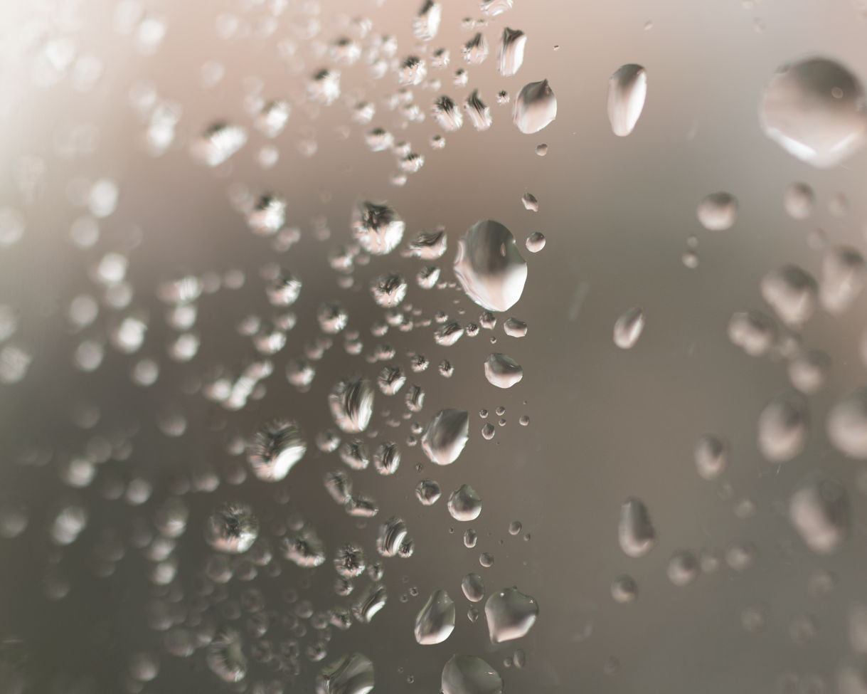 Gouttes d'eau sur une surface en verre, avec un flou artistique en arrière-plan.