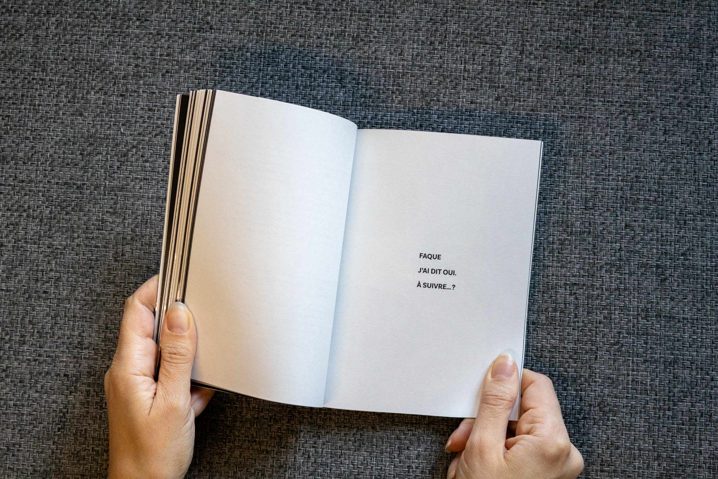 Une personne tient un livre ouvert avec une page blanche et un texte en français.