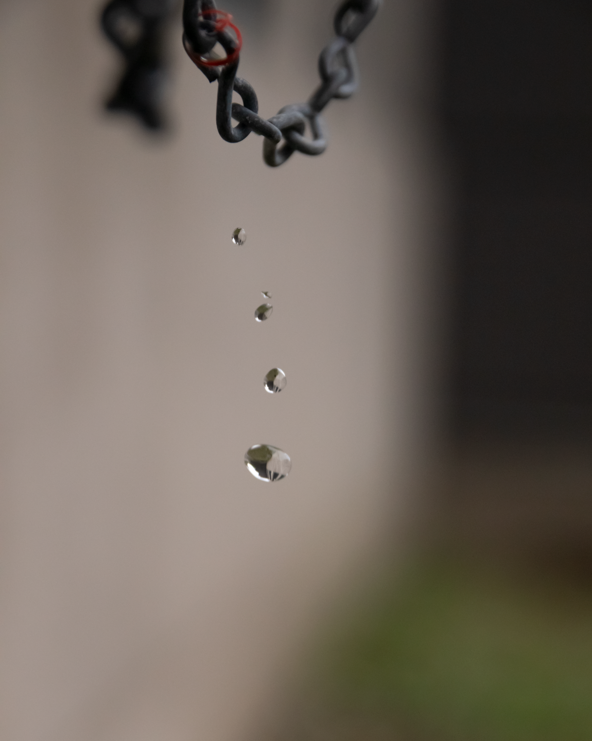 Gouttes d'eau tombant d'une chaîne métallique suspendue.