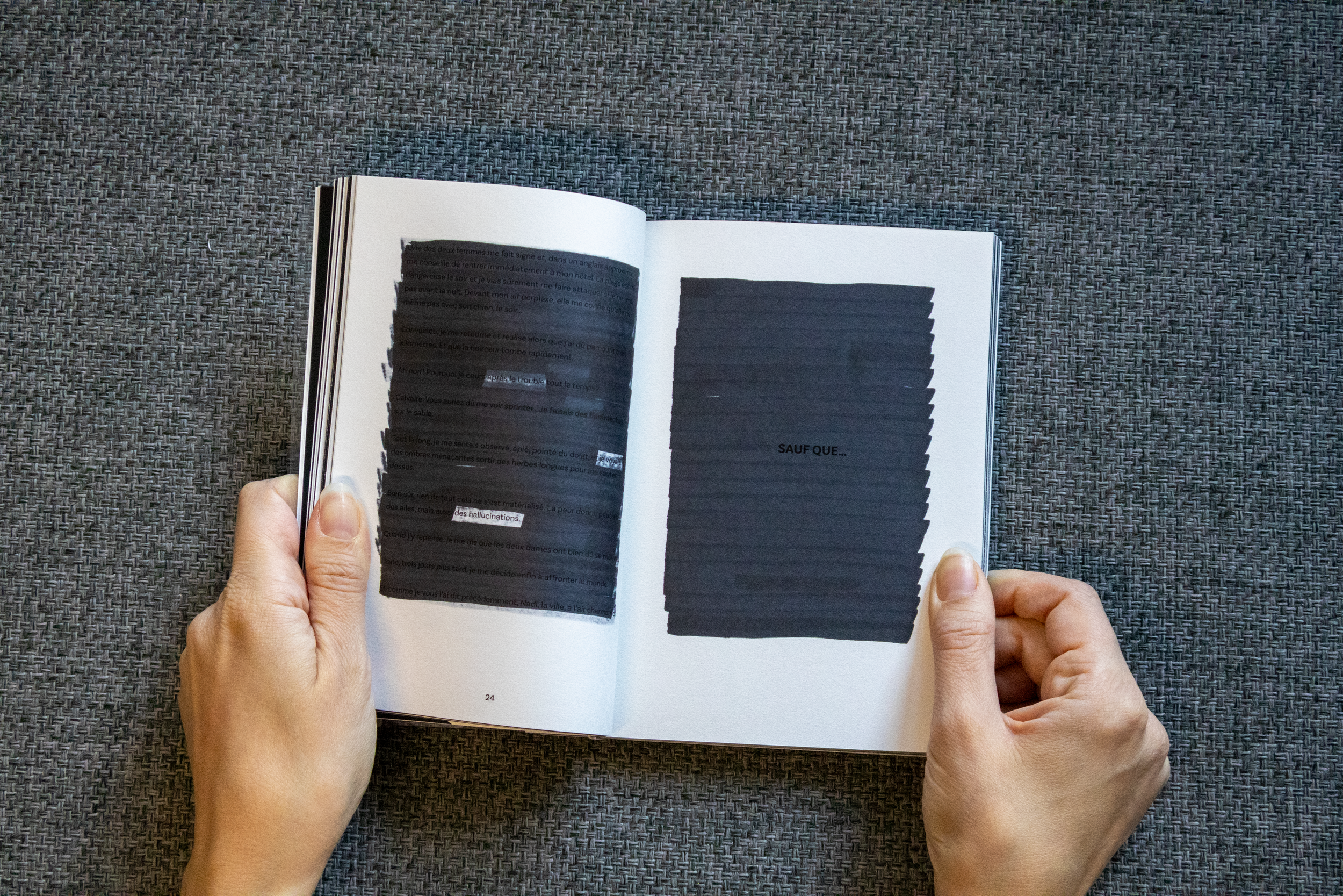 Une personne tient un livre ouvert avec deux pages visibles, chacune étant partiellement recouverte d'une zone noire. Sur la page de gauche, il y a une partie de texte en français, et sur la page de droite, il y a le texte "SAUF QUE...".