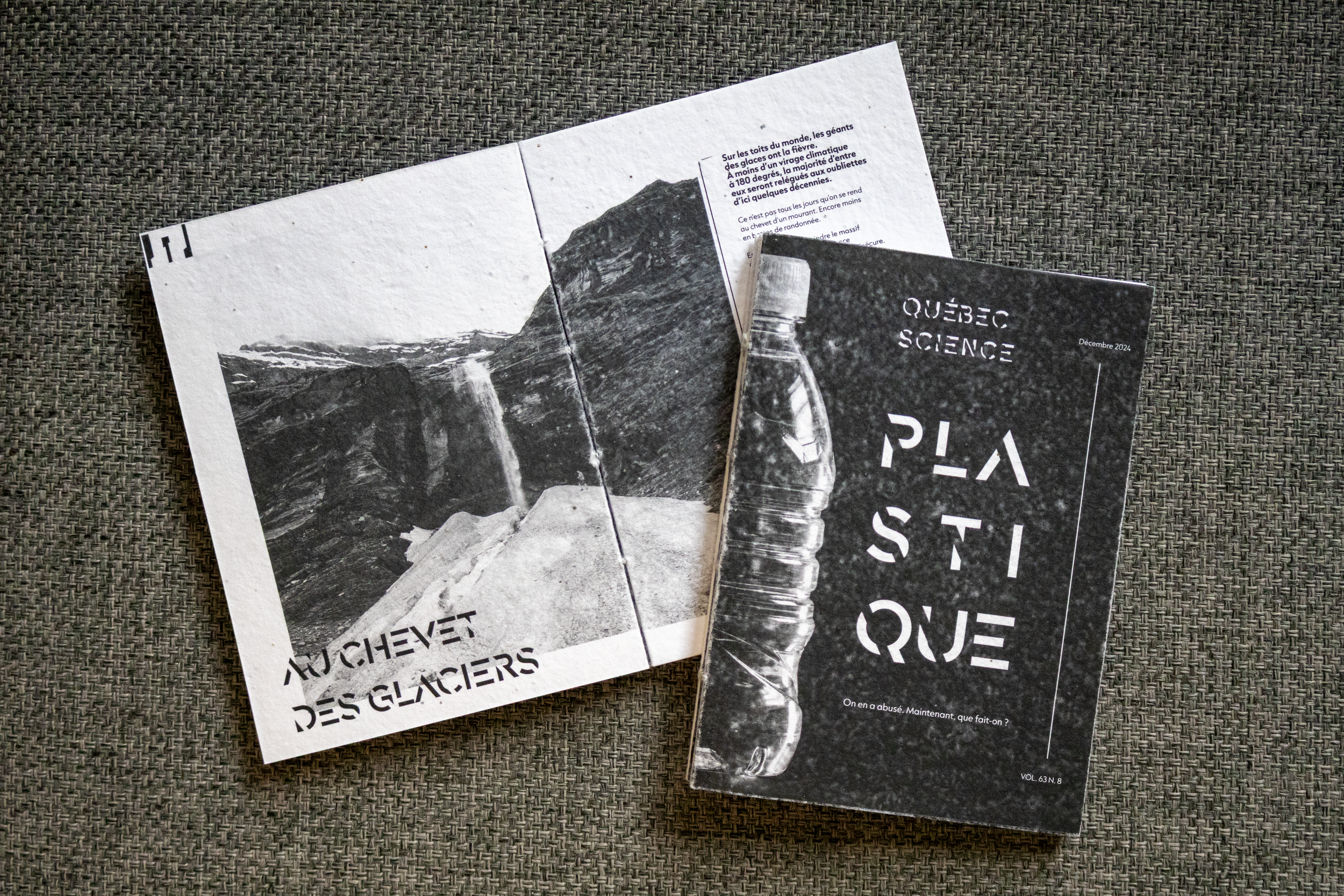 Deux exemplaires du magazine Québec Science : l’un ouvert sur une photo de glacier, l’autre montrant une bouteille en plastique et le titre “Plastique”, posés sur une surface tissée.
