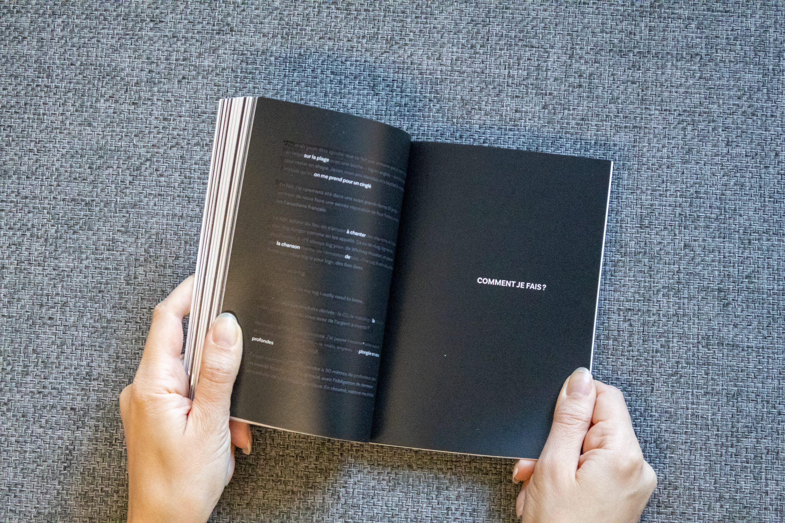 Une personne tient un livre ouvert avec la page de droite affichant 'COMMENT JE FAIS ?'