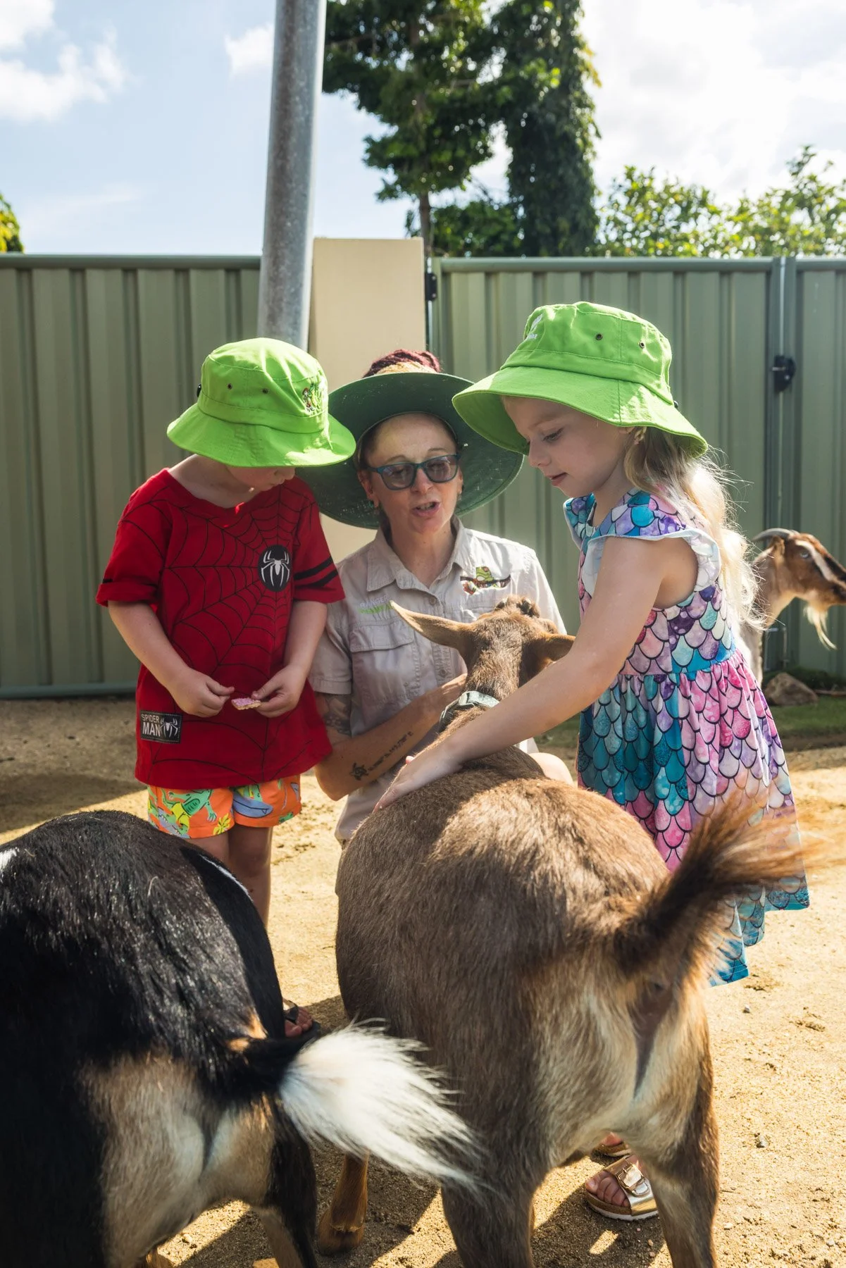 A woman reading a colorful book to a laughing young boy sitting on a bench in a room with educational posters on the wall.