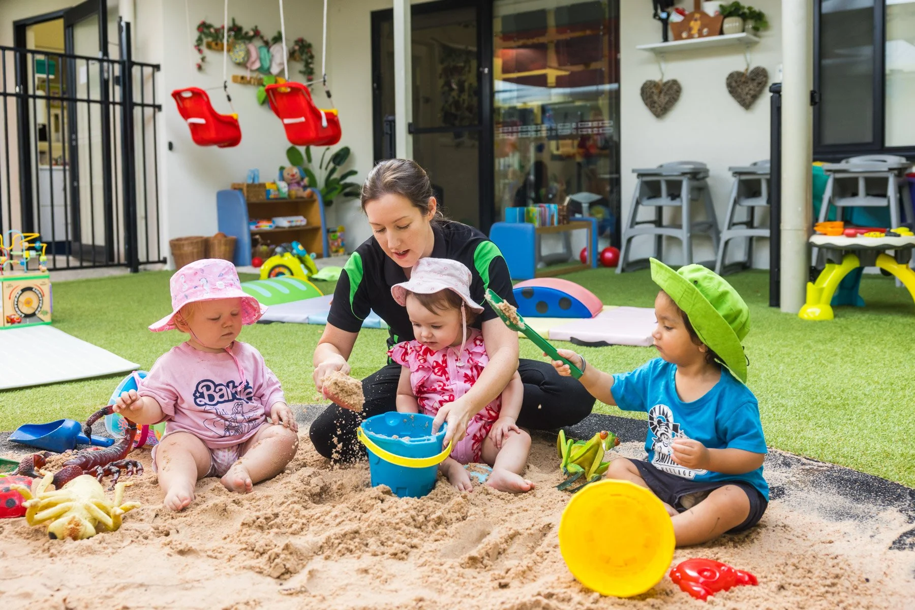 A woman reading a book to a laughing young boy sitting on a bench in a room with educational posters on the wall.