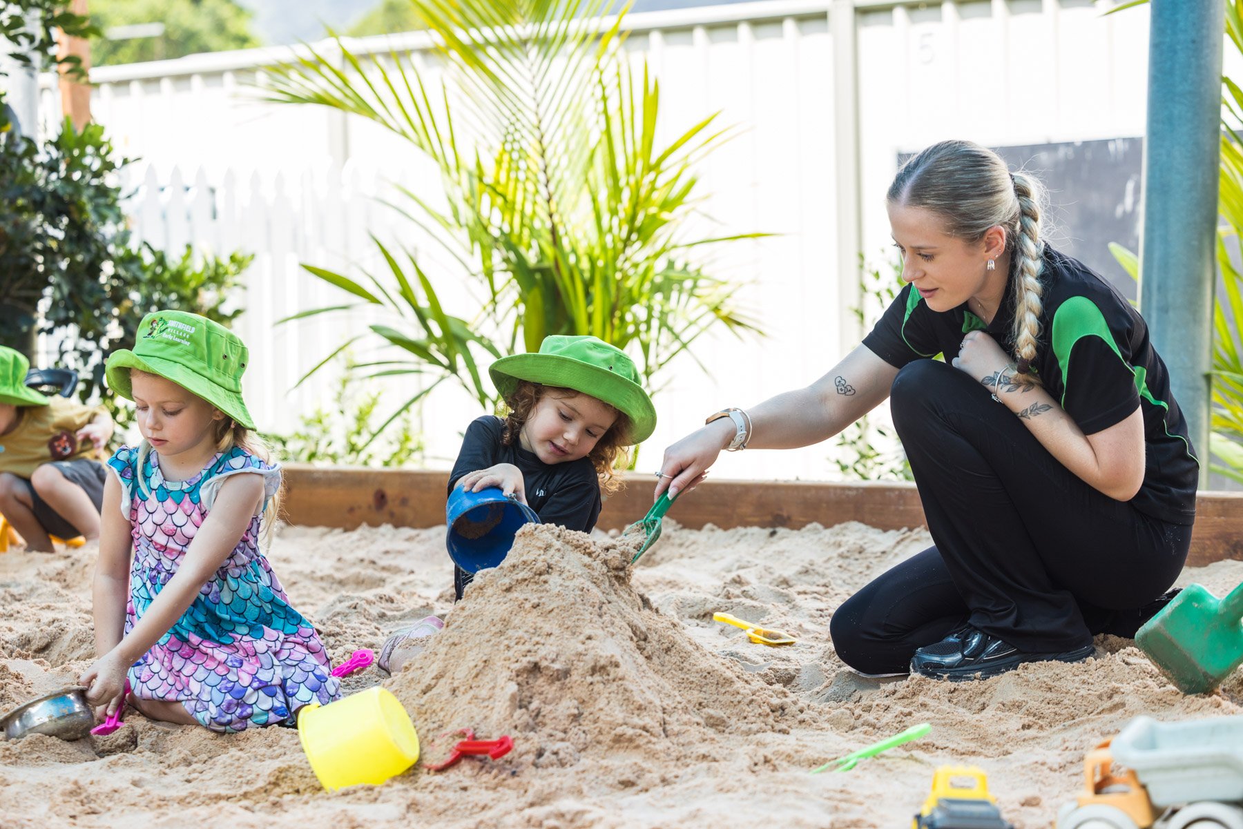 A child painting while a teacher looks on and helps