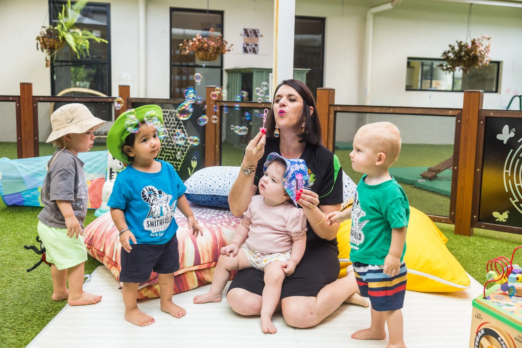 An early learning educator engaging in play with a group of toddlers at a childcare centre