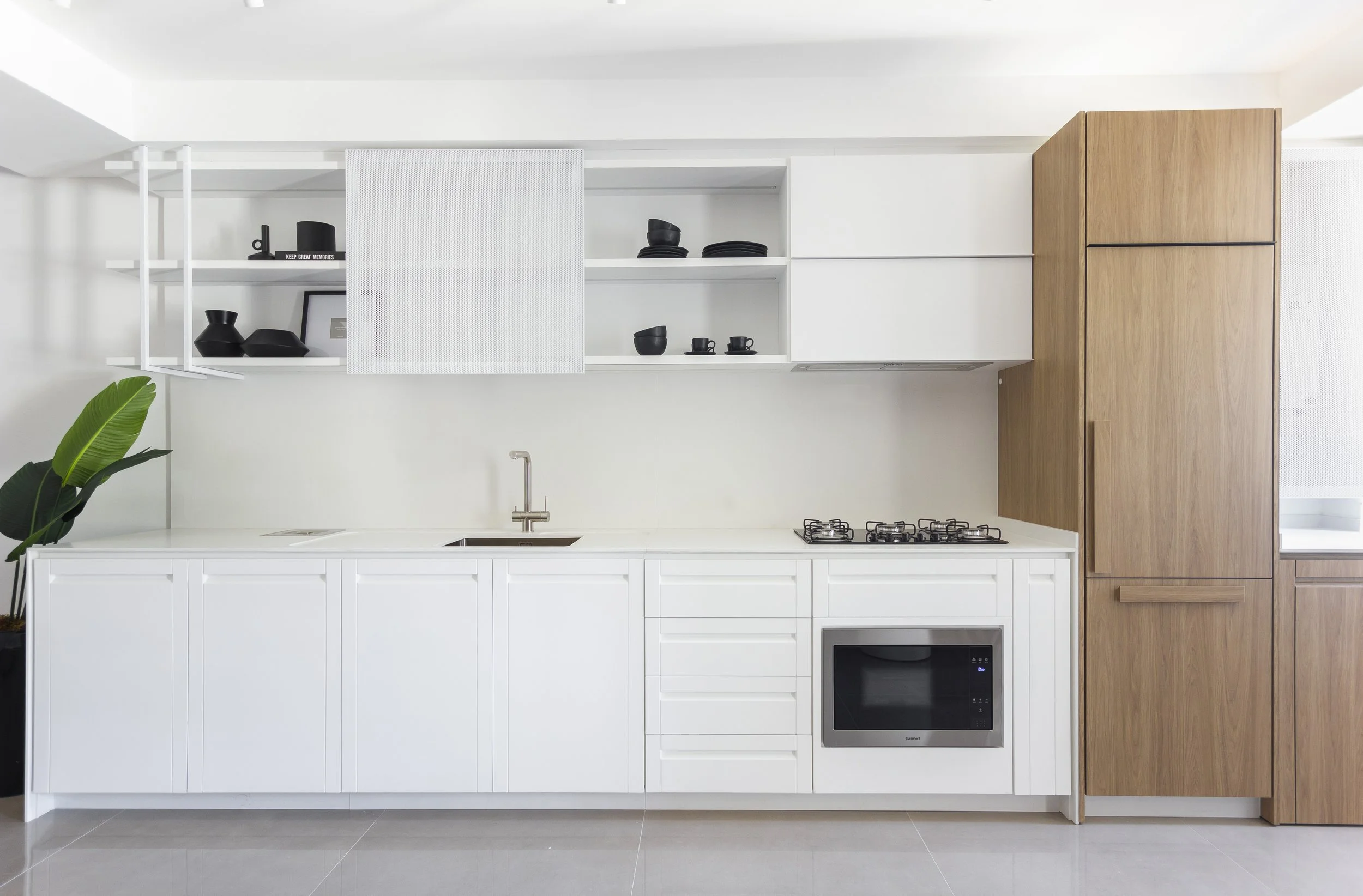 Cozinha moderna com armários brancos e de madeira, pia, micro-ondas e gás instalado na bancada, decoração minimalista com plantas verdes.