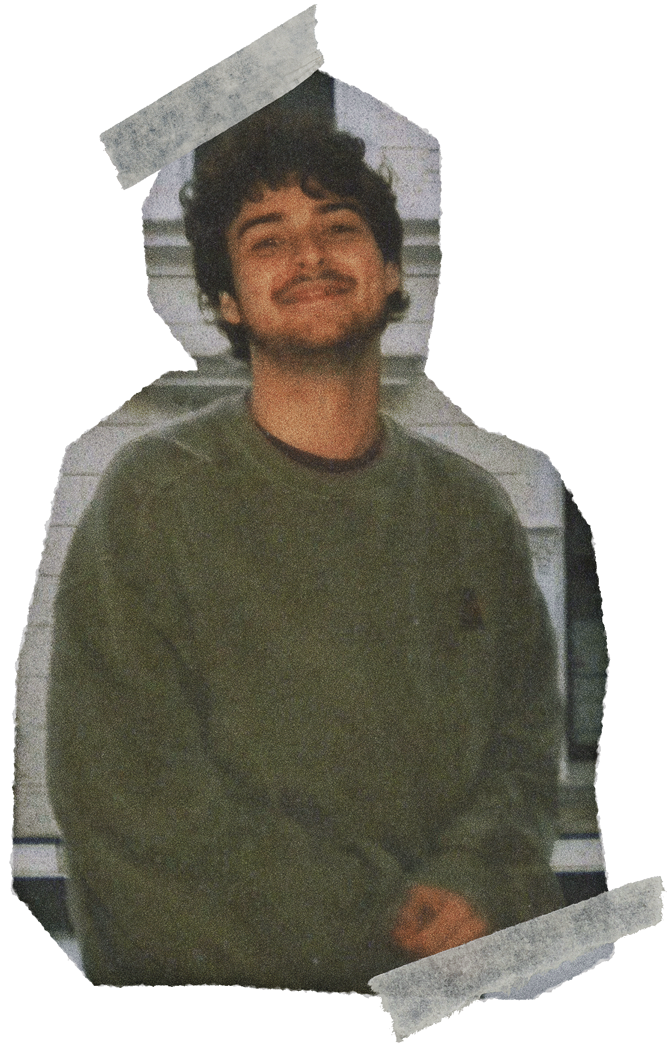 Junger Mann mit dunklem, lockigem Haar, smiling, trägt einen grünen Pullover und sitzt vor einem weißen, horizontalen Bord.