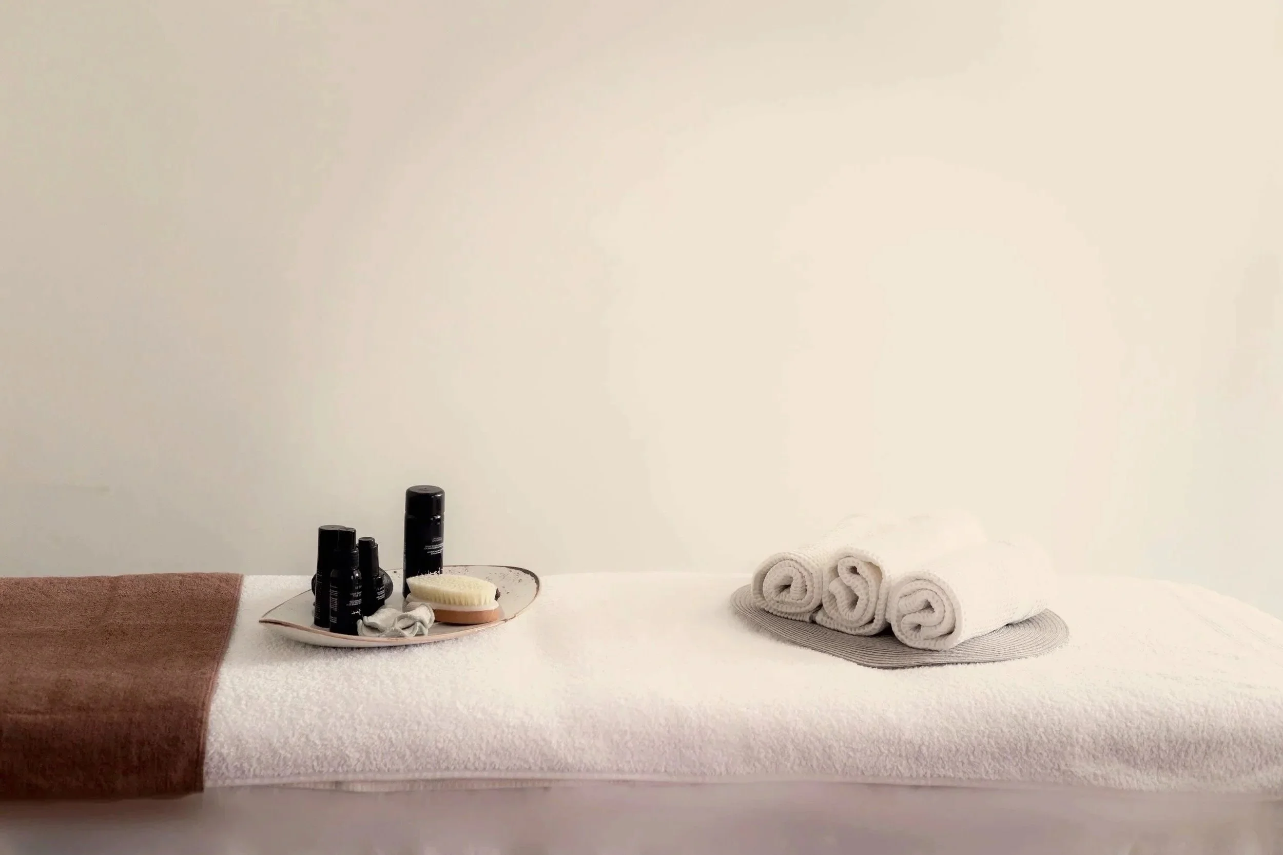 Setup di spa o bagno con prodotti come bottiglie di oli o lozioni, spugne e asciugamani arrotolati.