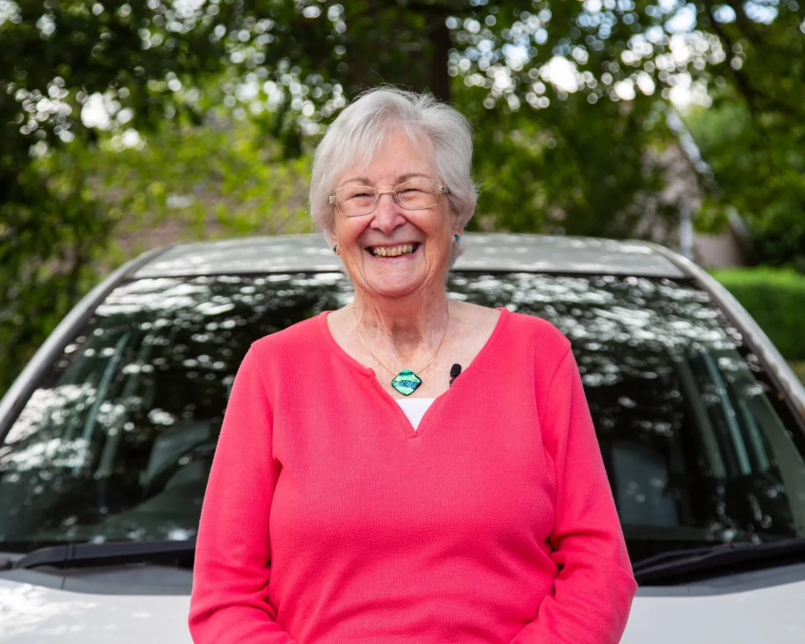 Volunteer driver Carole smiling in front of her car