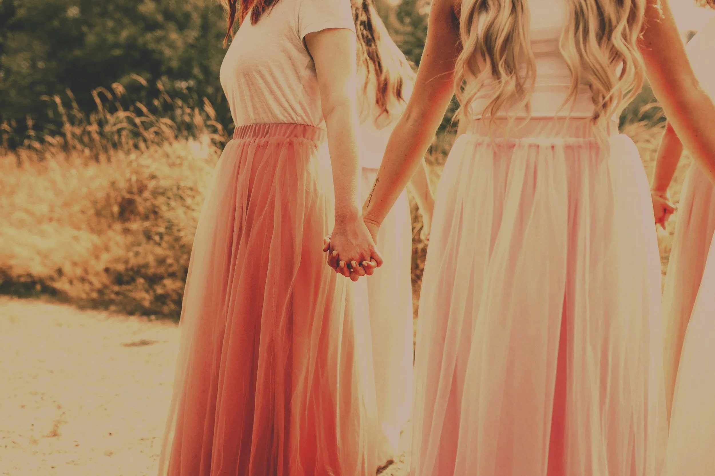 Two women holding hands outdoors, symbolizing sisterhood, emotional support, and healing community for women rising together for narcissistic abuse support women's healing circle and manifestation circle. 