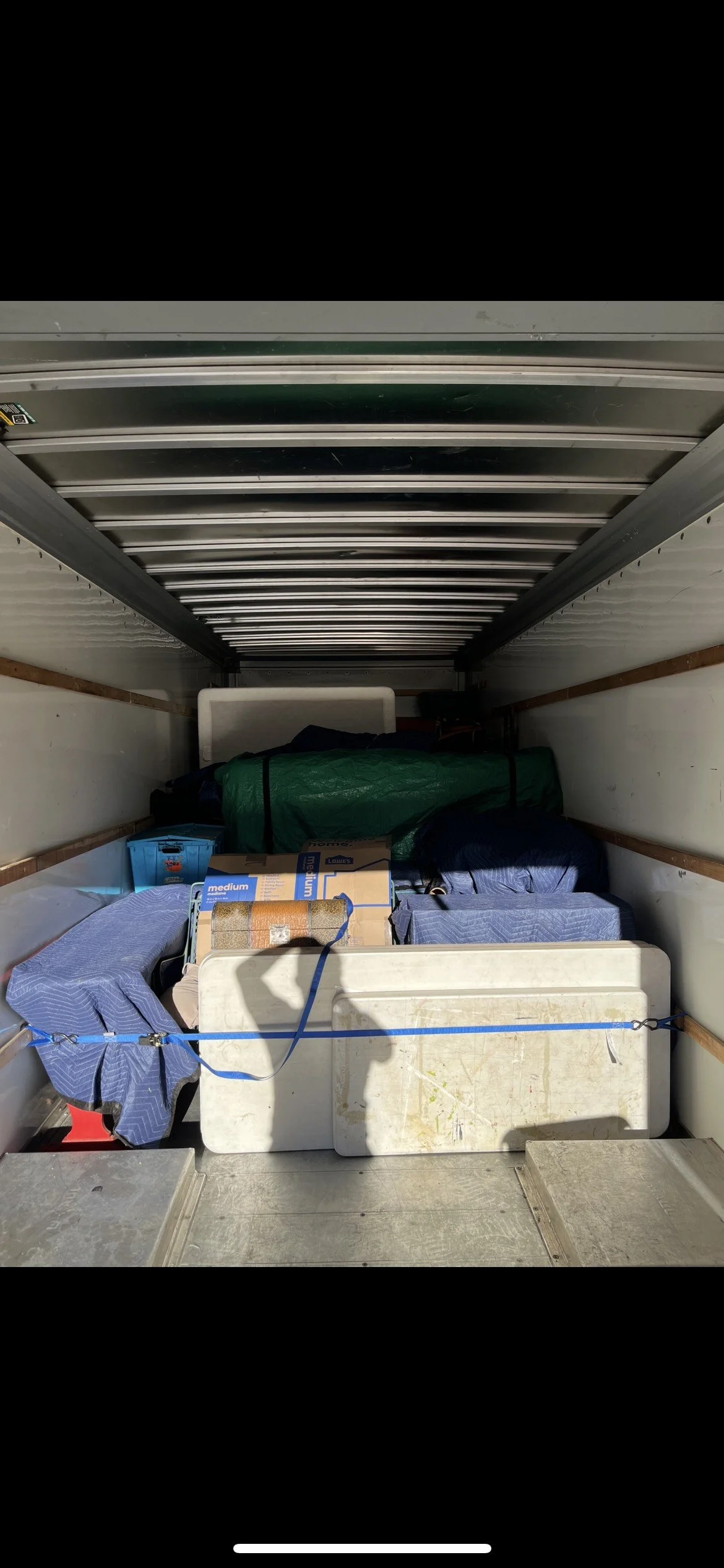 Interior of a moving truck filled with various boxes, bags, and other stored items.