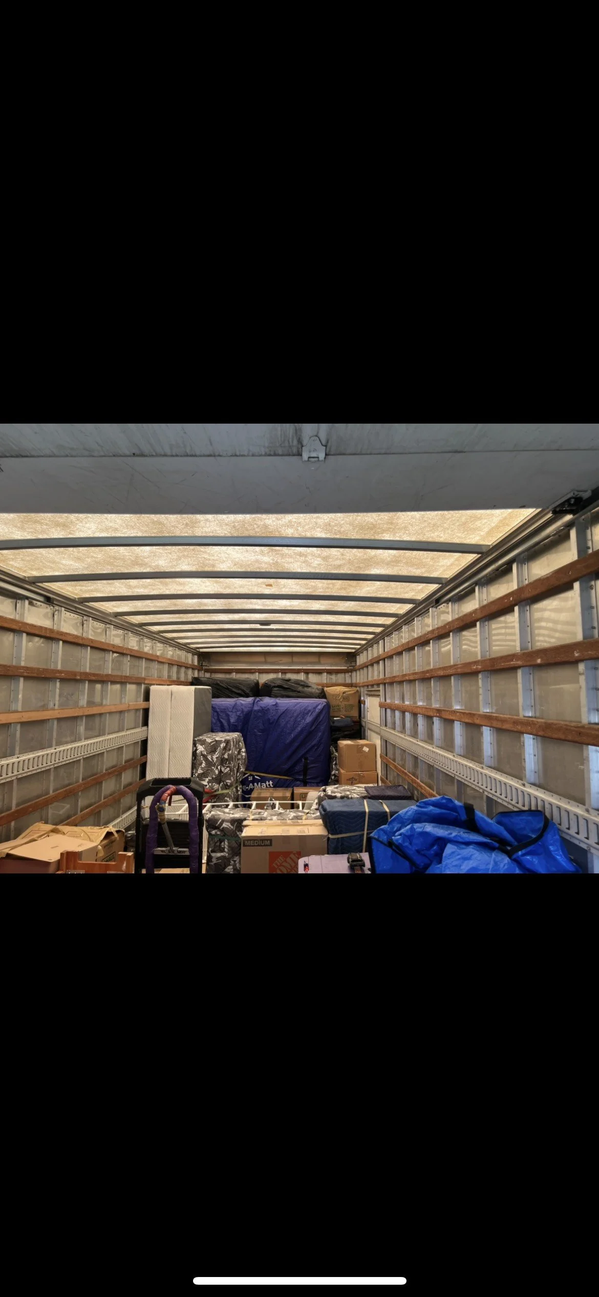 Empty moving truck filled with boxes, bags, and furniture, ready for transport.