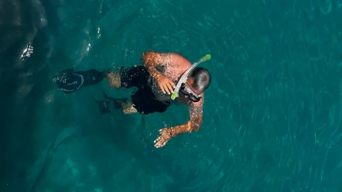 Een persoon met een snorkel en zwemvliezen onder water.
