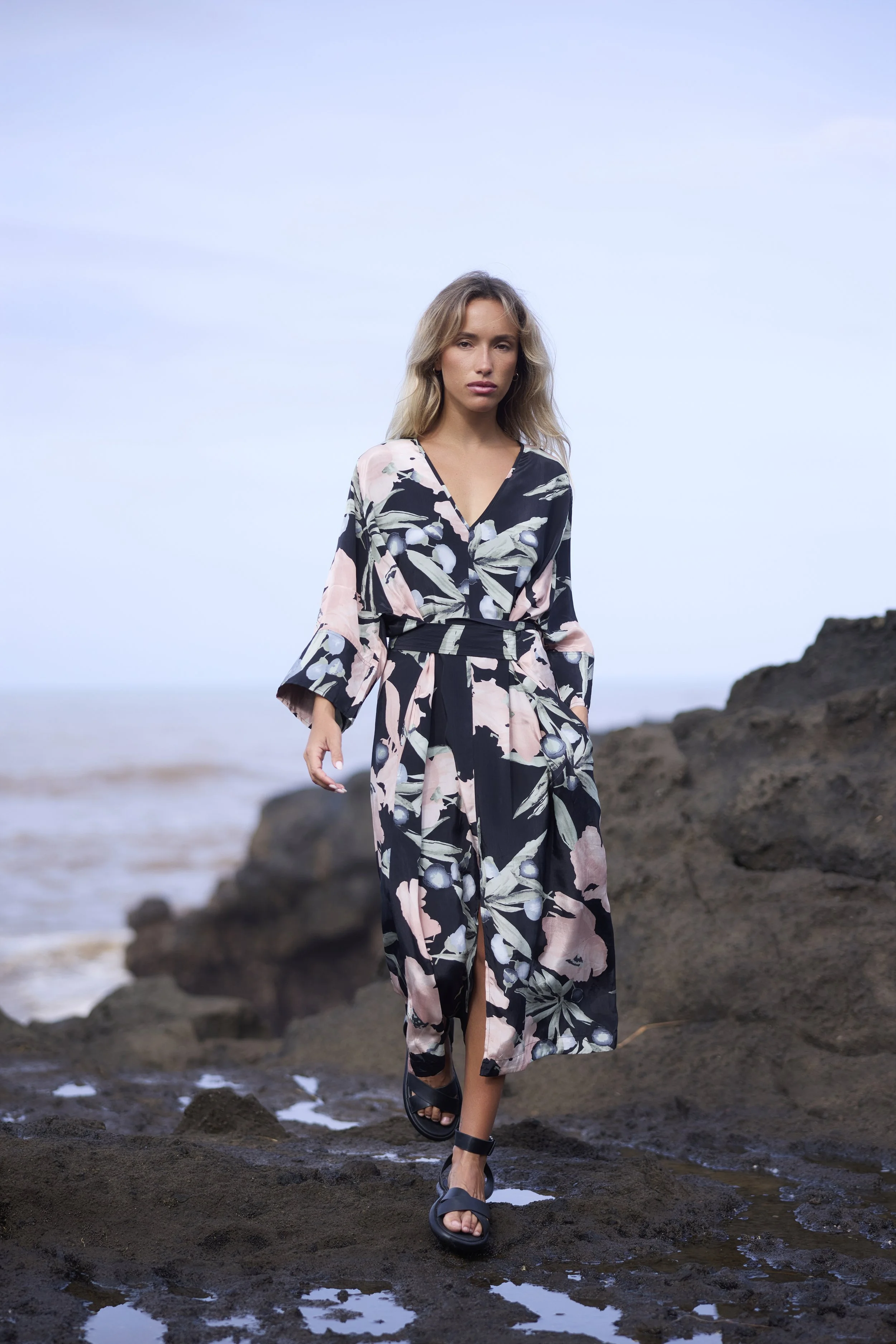 Woman in a floral dress walking on rocky shoreline