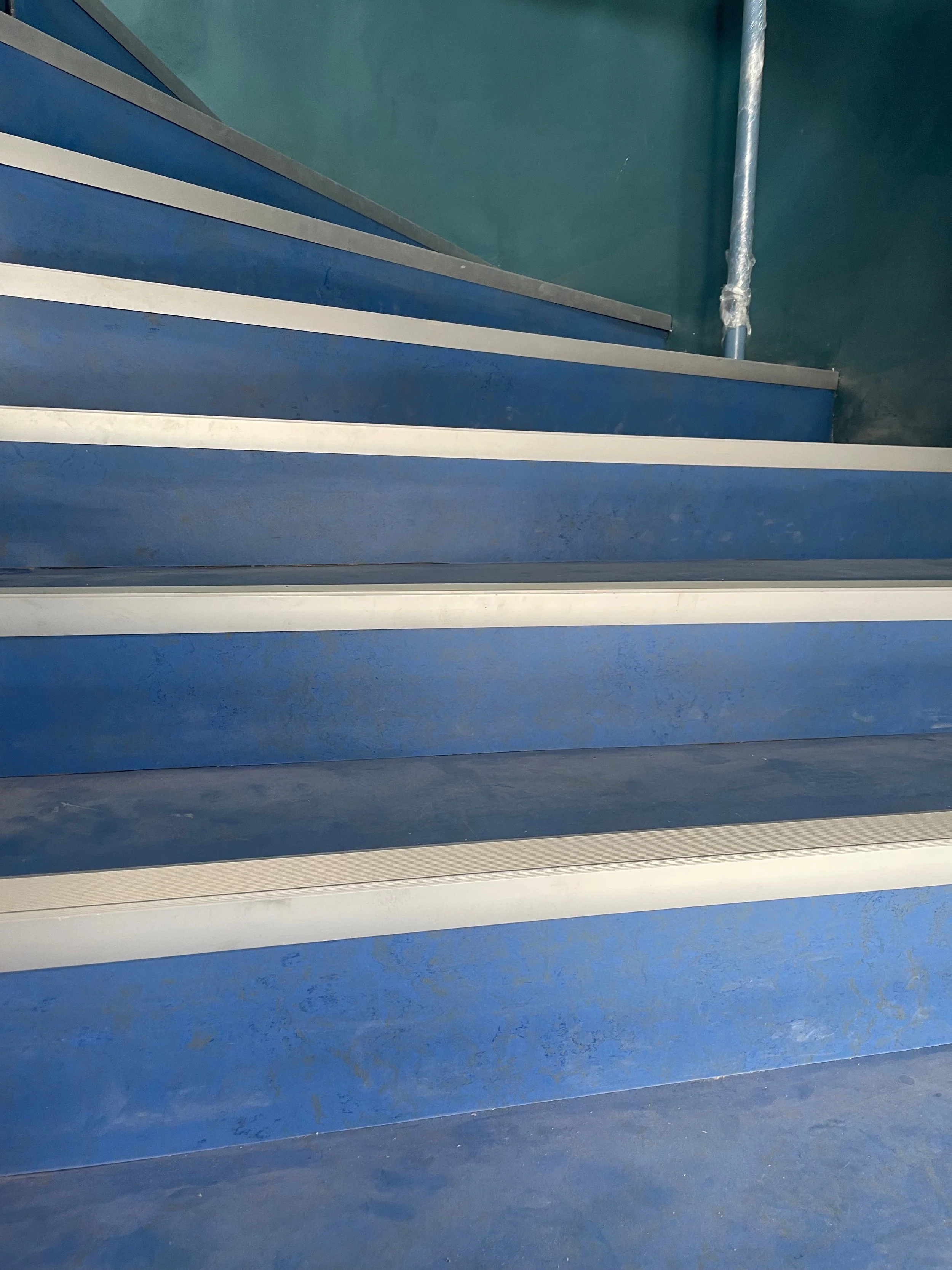 Mise en accessibilité d’un escalier avec revêtement PVC antidérapant et nez de marche contrastés, conforme aux normes ERP et PMR.