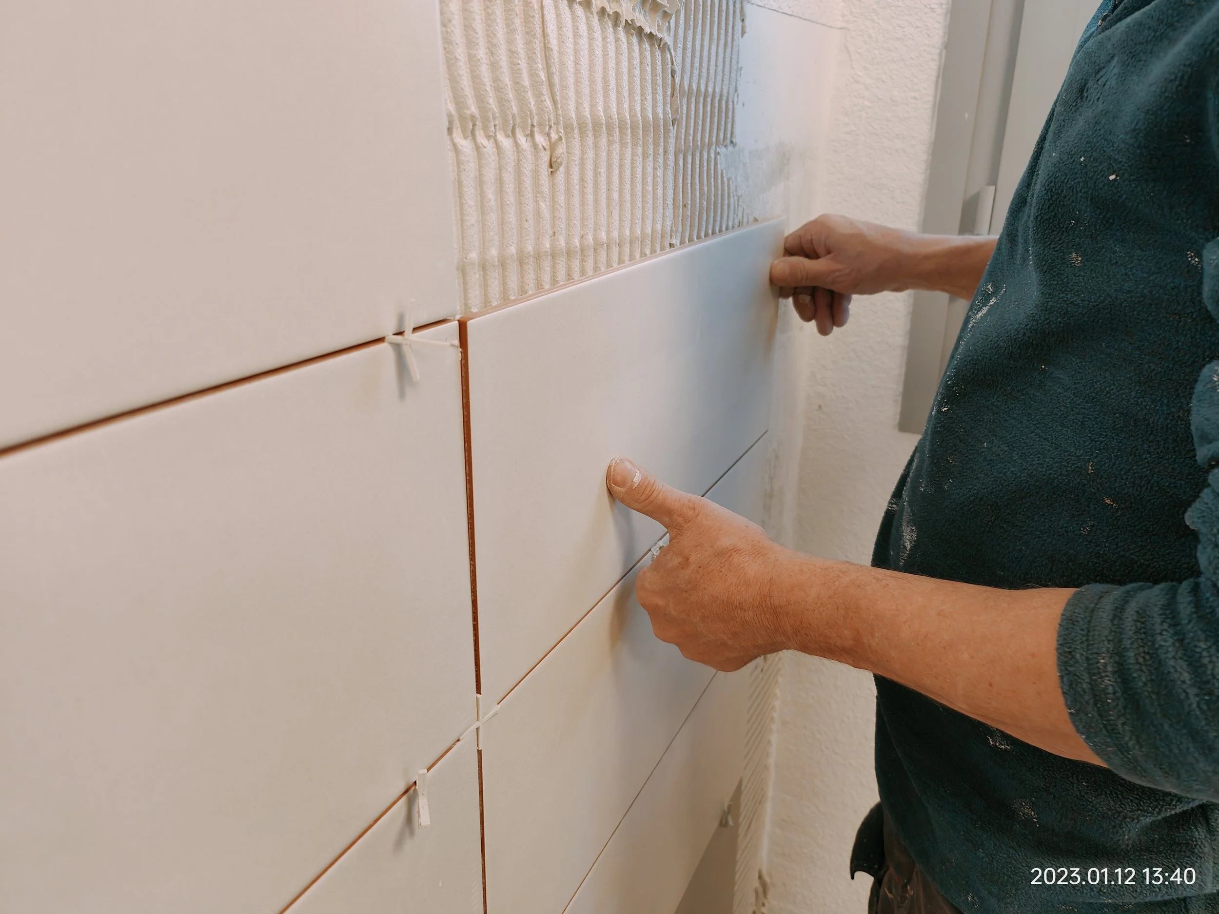 Carreleur professionnel réalisant la pose et le contrôle précis de carrelage mural lors de travaux de rénovation intérieure.