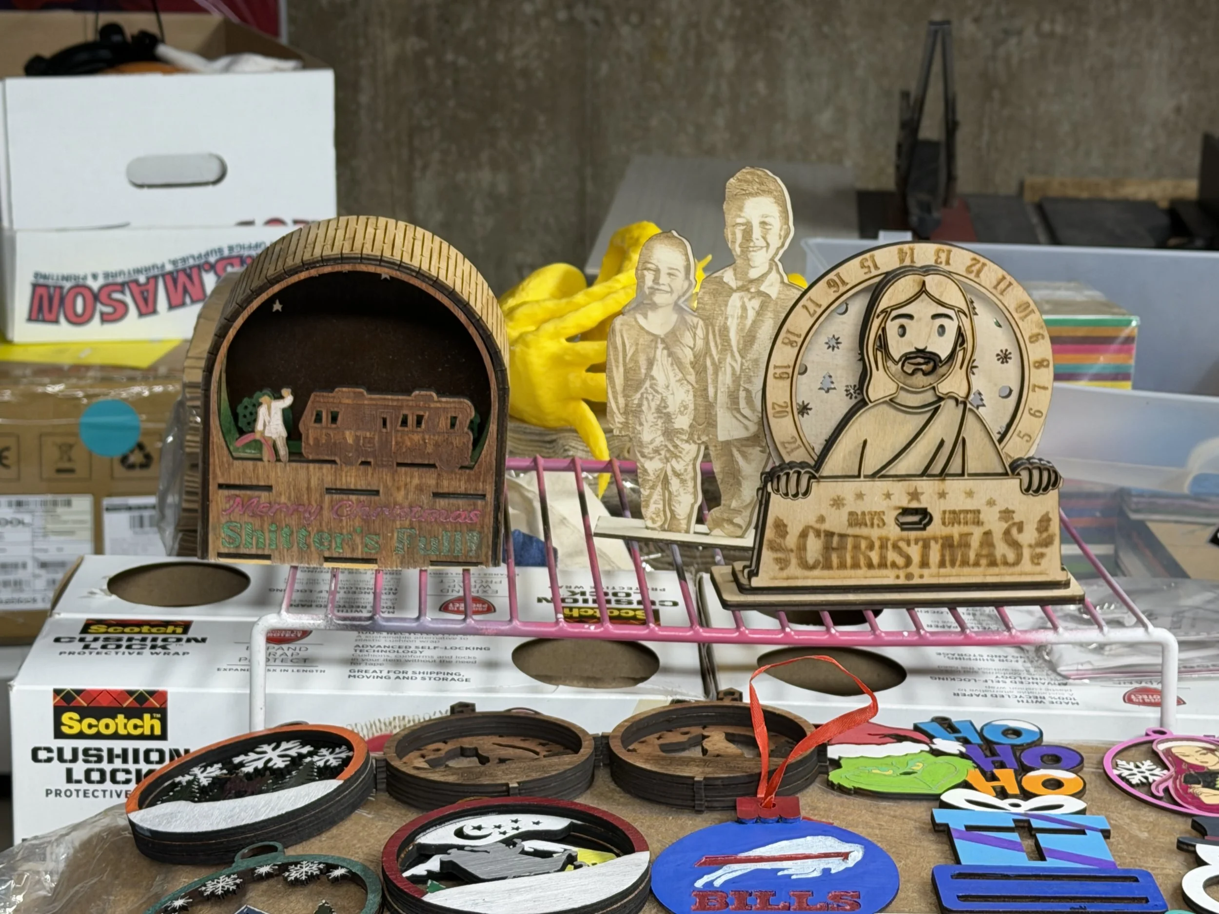 Assorted Christmas ornaments and decorations, including wooden figures, logos, and festive designs, displayed on a table.
