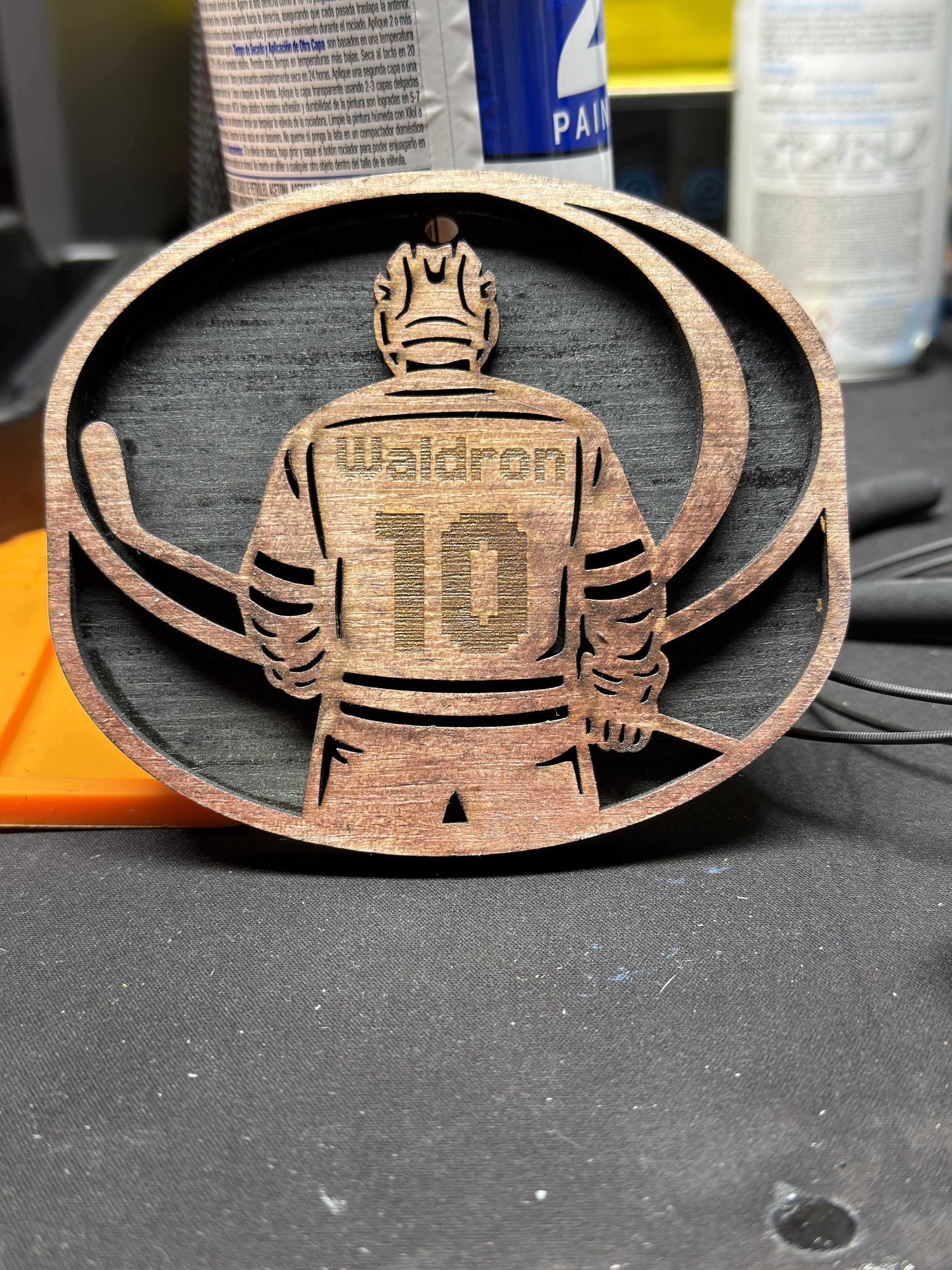 Wooden hockey player decoration with the name Walden and the number 10, holding a hockey stick, behind an oval frame.