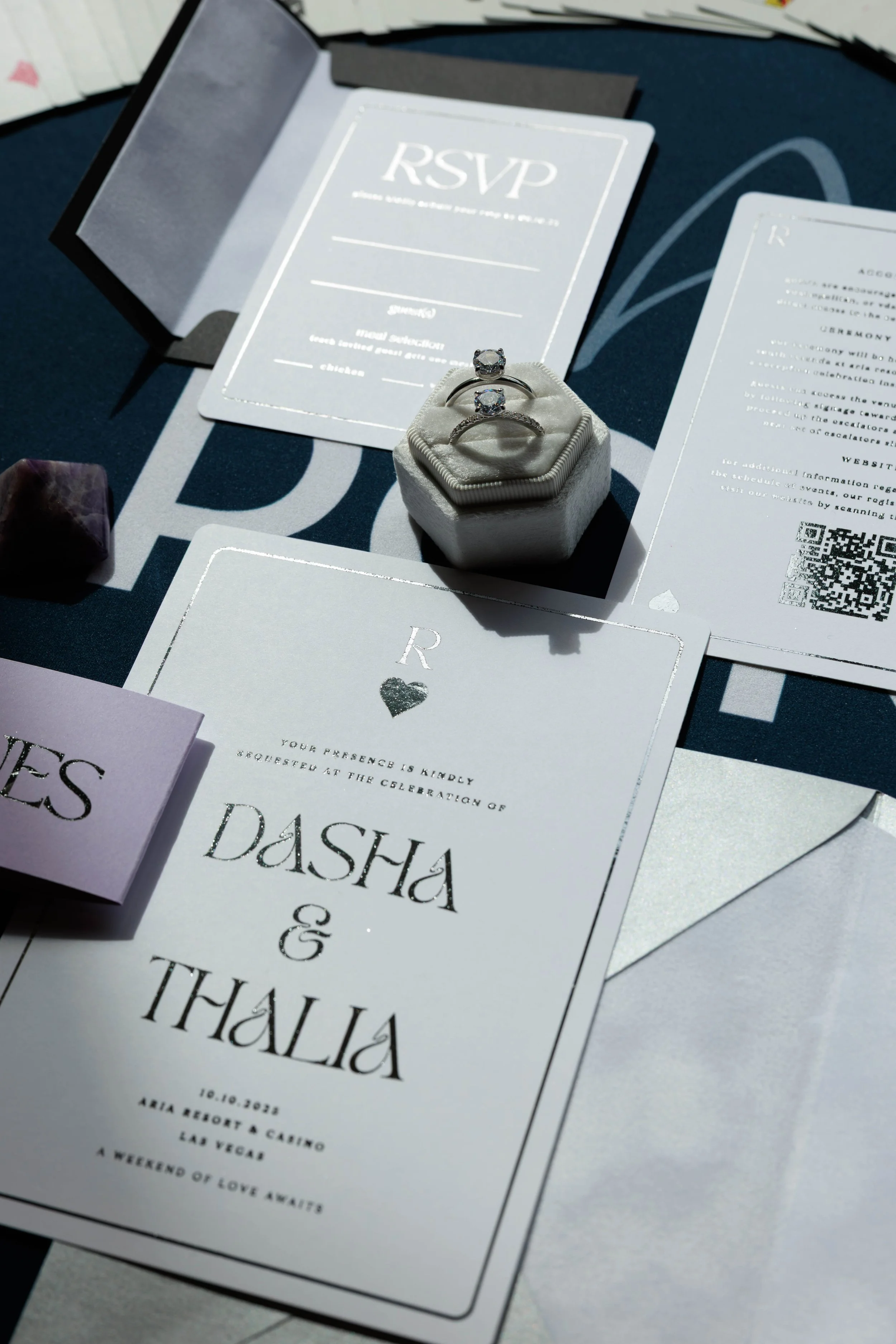 Wedding invitation with rings and RSVP card on a table.