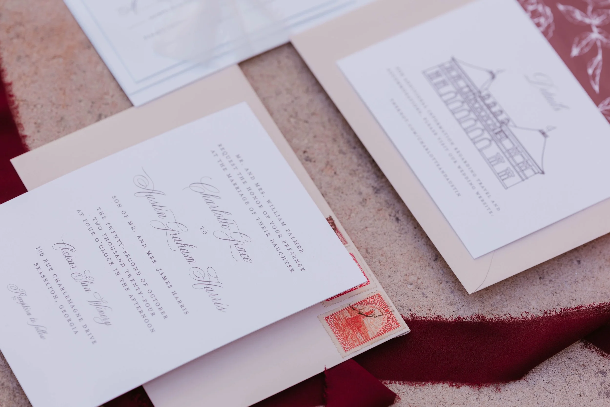 Wedding invitation and reception details on elegant stationery, with a vintage red stamp on a textured surface.